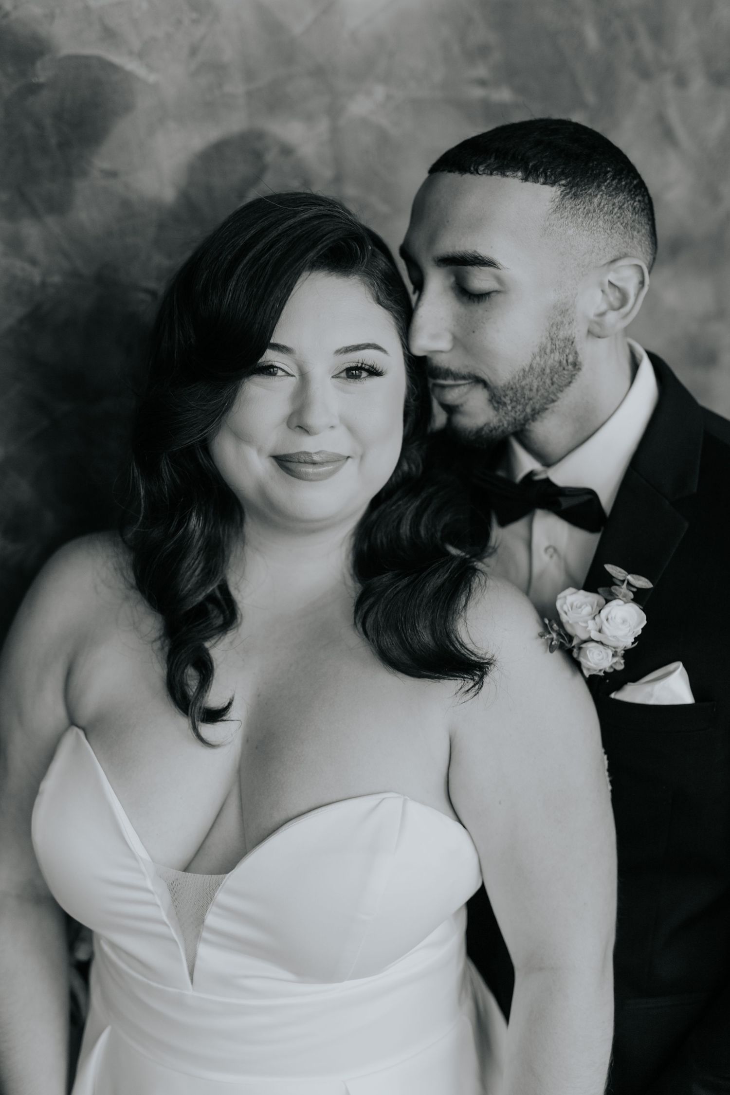 Black and white portrait of smiling bride with groom nuzzling her cheek in tuxedo at Hotel Haya in Tampa.