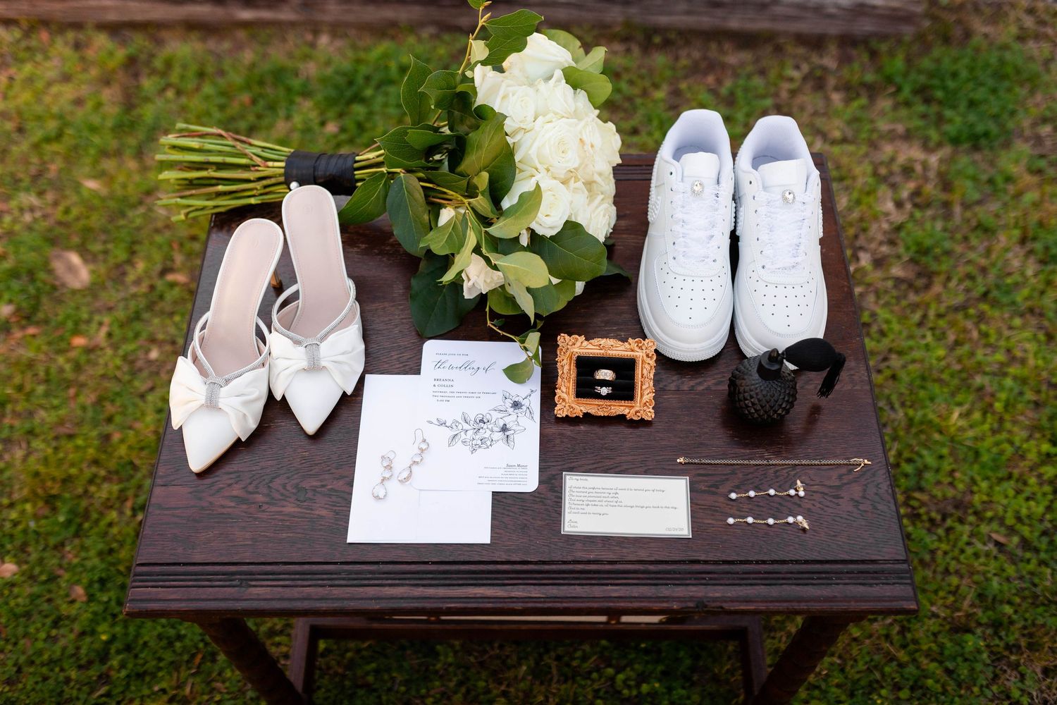 Wedding flat lay featuring bridal heels, white sneakers, bouquet, rings, and stationery on a wooden table.