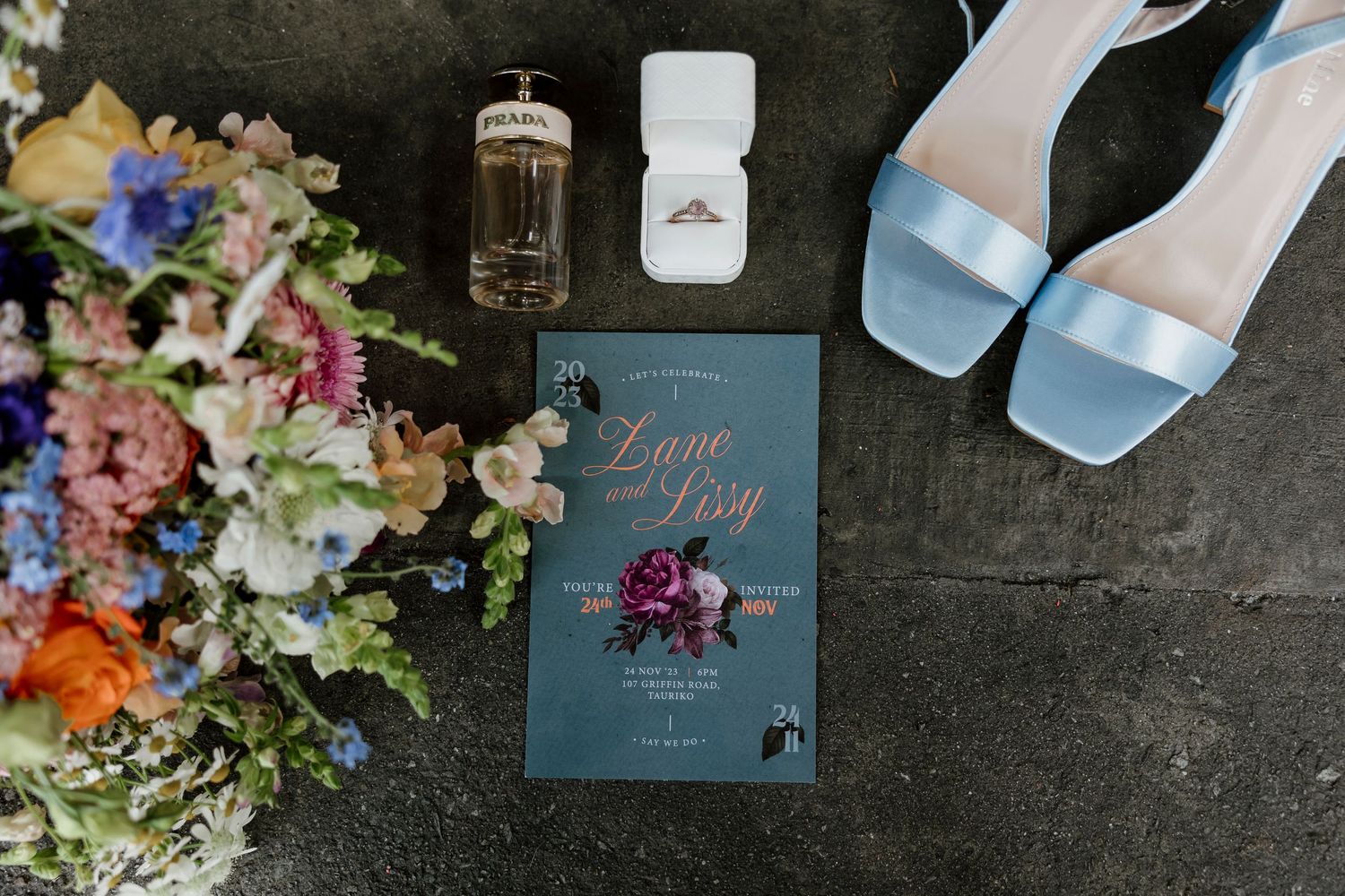Bridal flatlay with wedding invitation, diamond ring, blue heels, perfume and wildflower bouquet — Oh Joy! Photography Tauranga