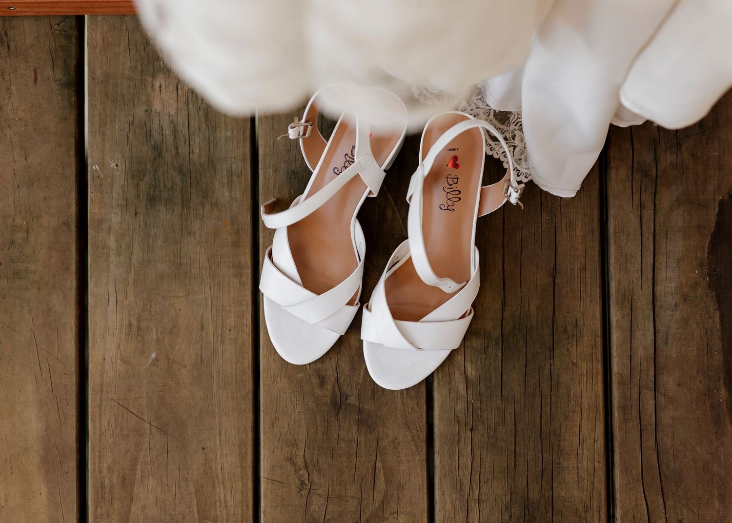 Detail shot of white strappy bridal heels on a rustic wooden deck — Oh Joy! Photography Tauranga