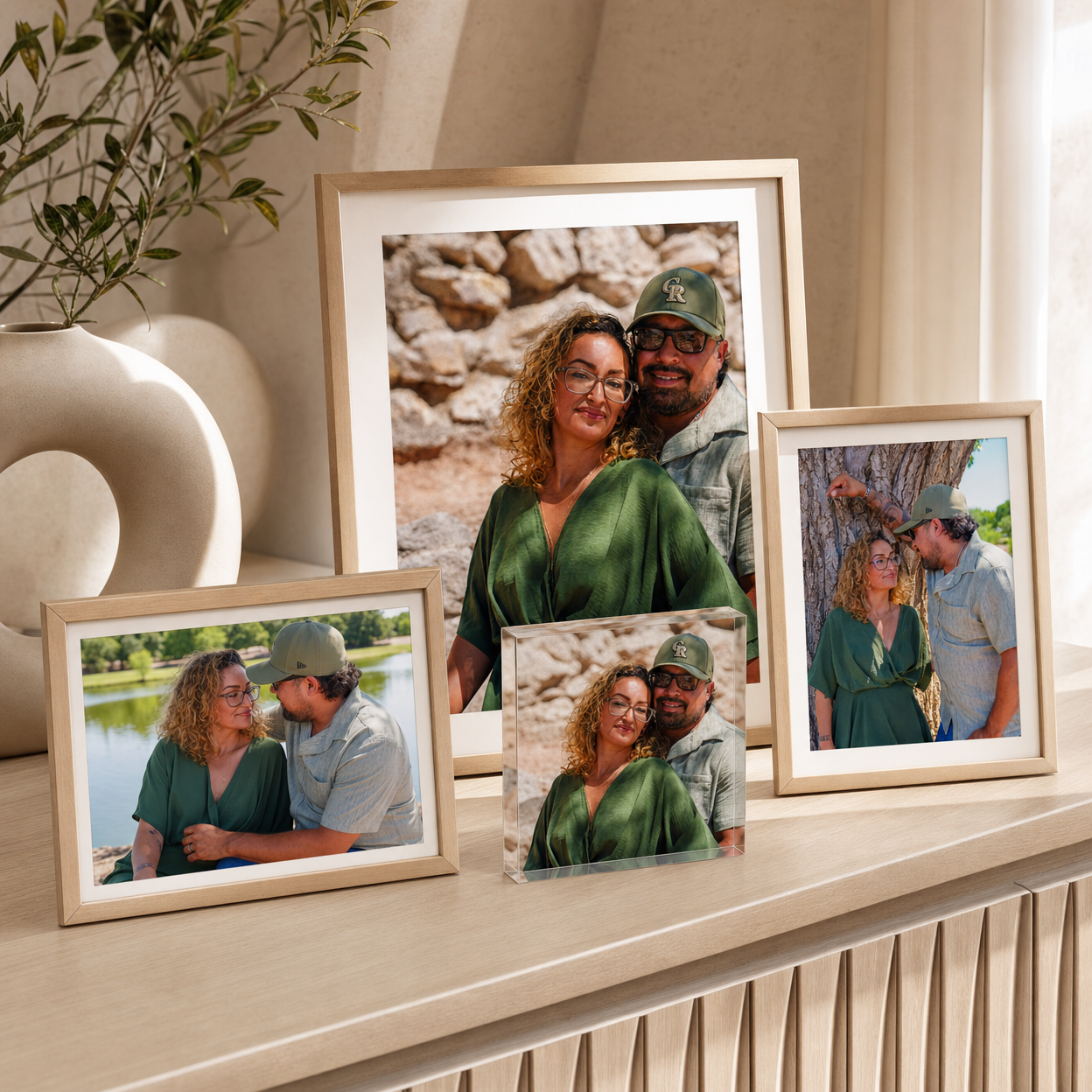 Four wooden photo frames displaying a couple in green outfits arranged on a shelf with a vase.