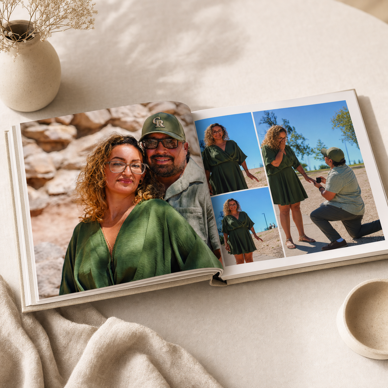 Open photo book displaying a couple portrait and engagement proposal photos on a white table with soft natural lighting.