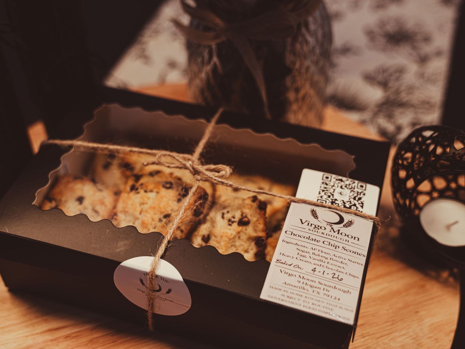 Artisan baked goods in a black gift box tied with twine, branded with Virgo Moon logo on a wooden surface.
