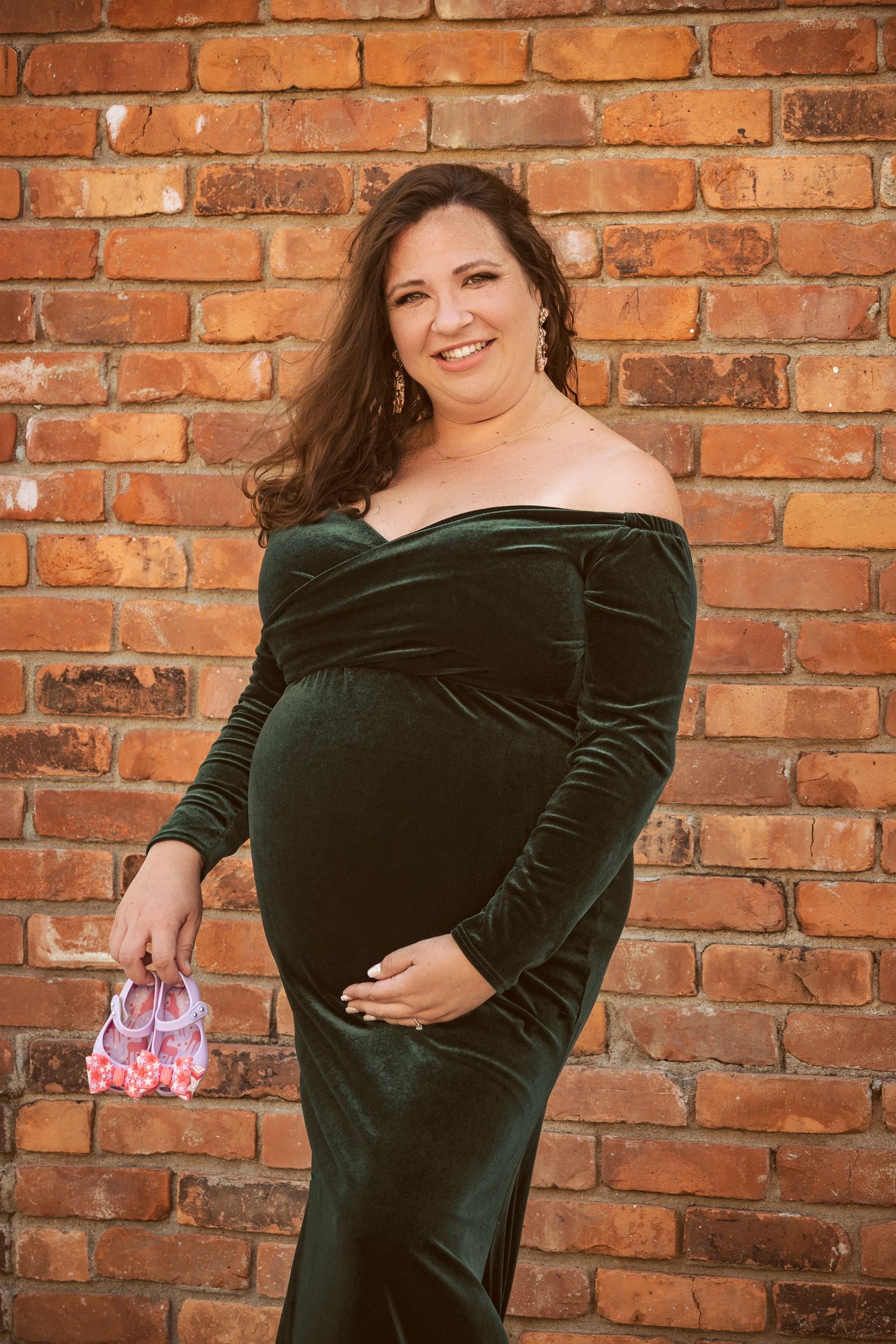 Pregnant mother smiling beside a brick wall during a maternity session by a Central Florida Photographer.