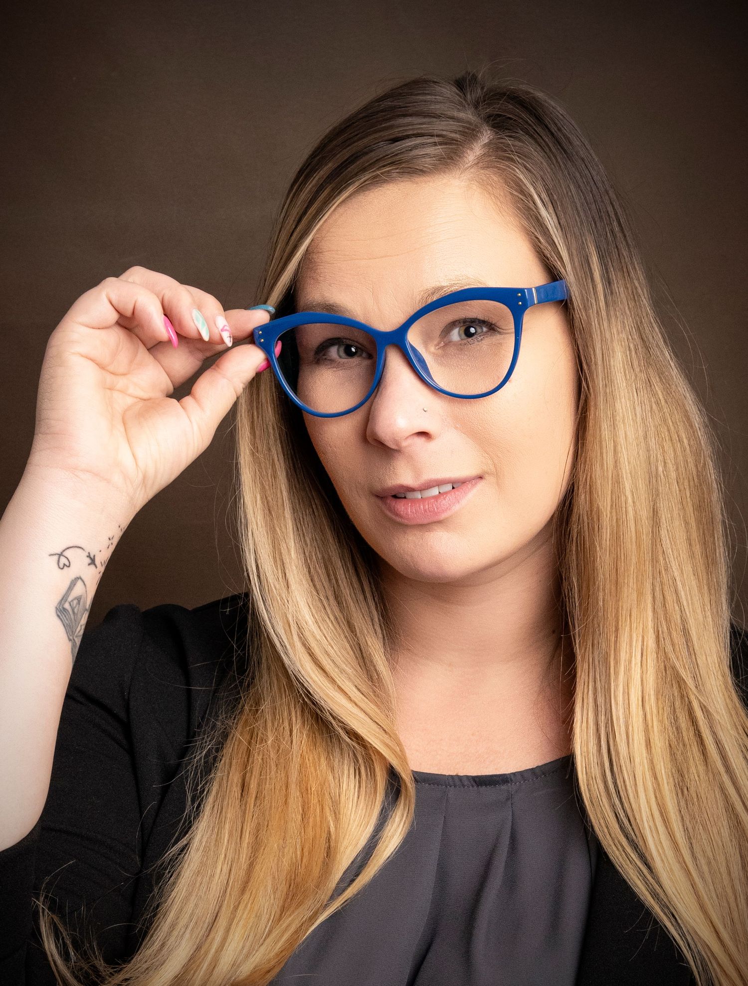 Professional woman adjusting blue glasses during a business headshot session by a Central Florida Photographer.