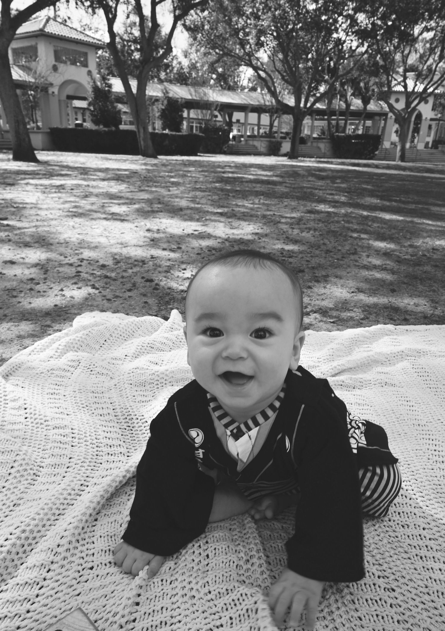 Black and white photo of a smiling baby crawling outdoors during a milestone session by a Central Florida Photographer.