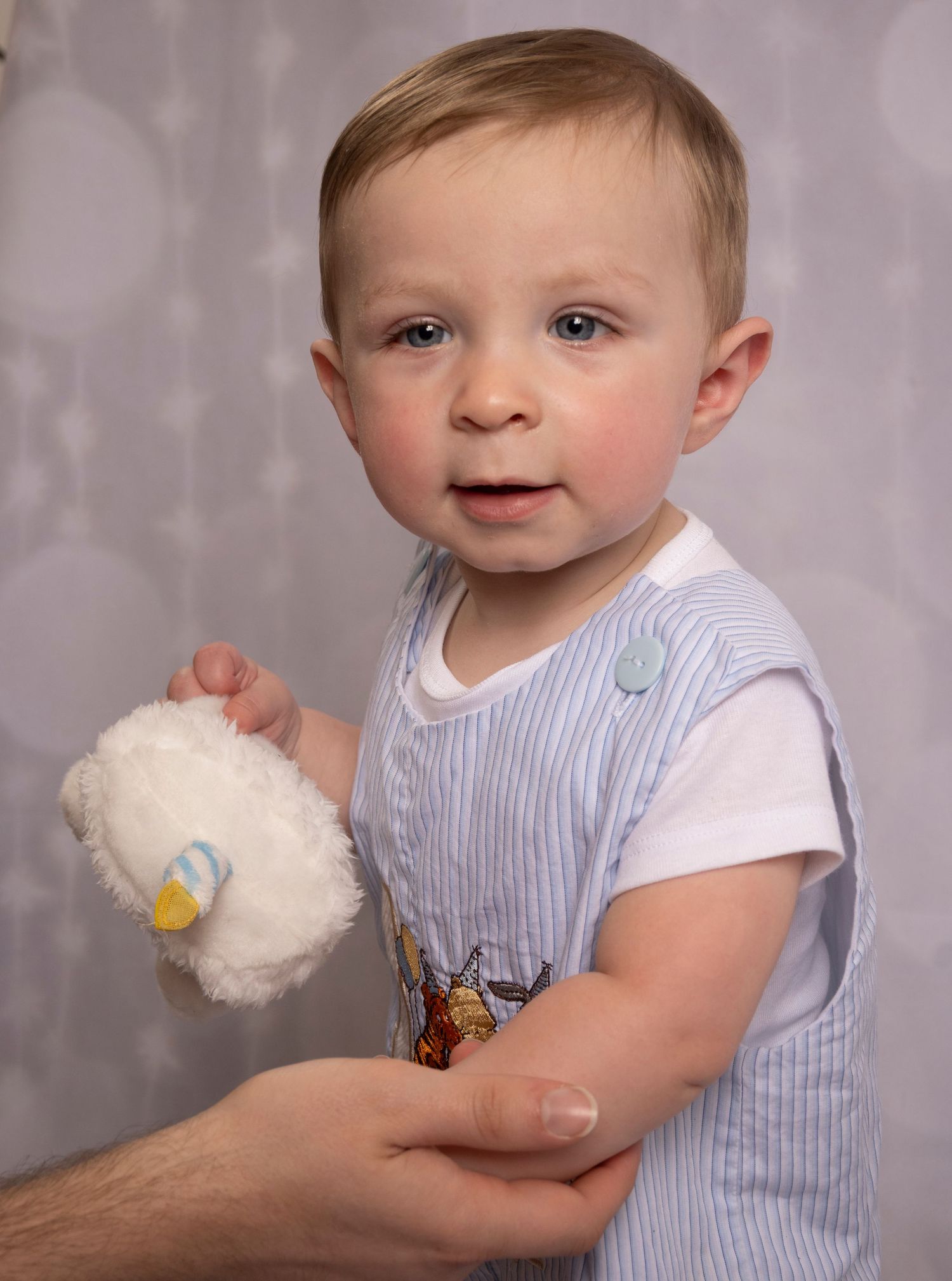 Curious toddler holding a plush cupcake during a studio milestone portrait by a Central Florida Photographer.