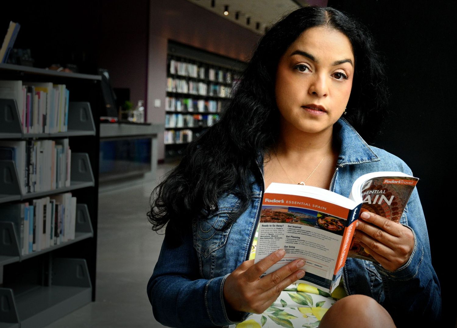 Student reading a book in a library during a senior portrait session by a Central Florida Photographer.