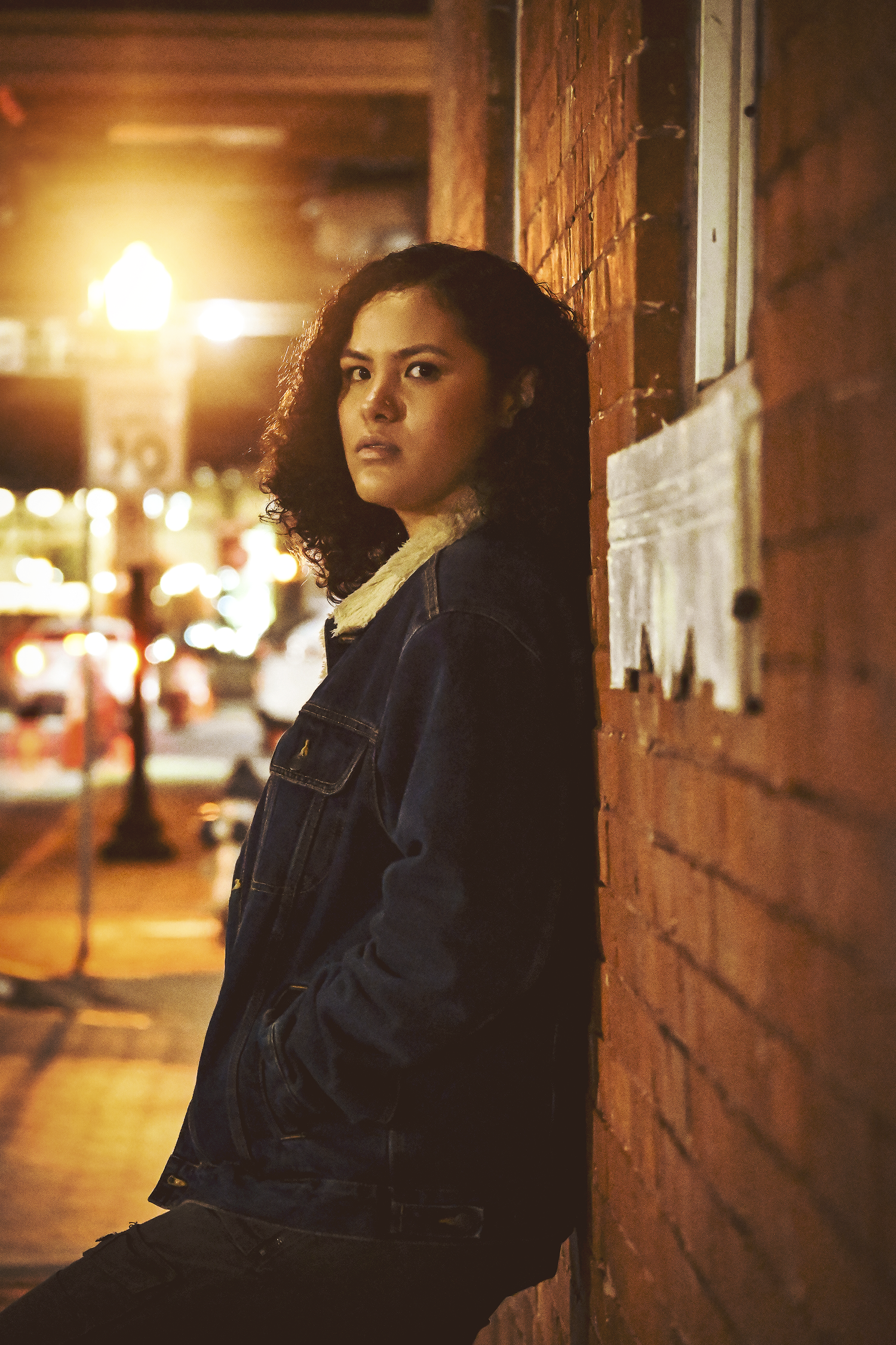 Senior girl leaning against a brick wall at night during an urban portrait session by a Central Florida Photographer.