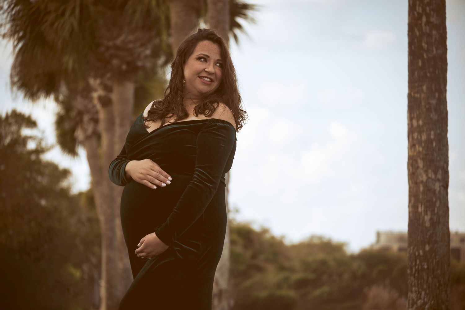 Pregnant mother smiling outdoors during a golden hour maternity session by a Central Florida Photographer.
