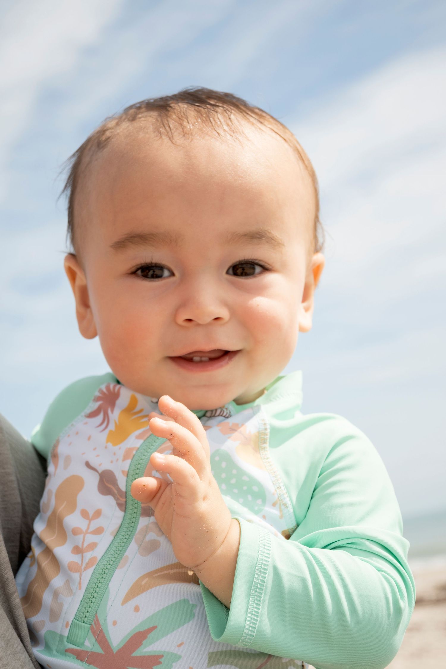 Smiling baby at the beach during a family milestone session captured by a Central Florida Photographer.