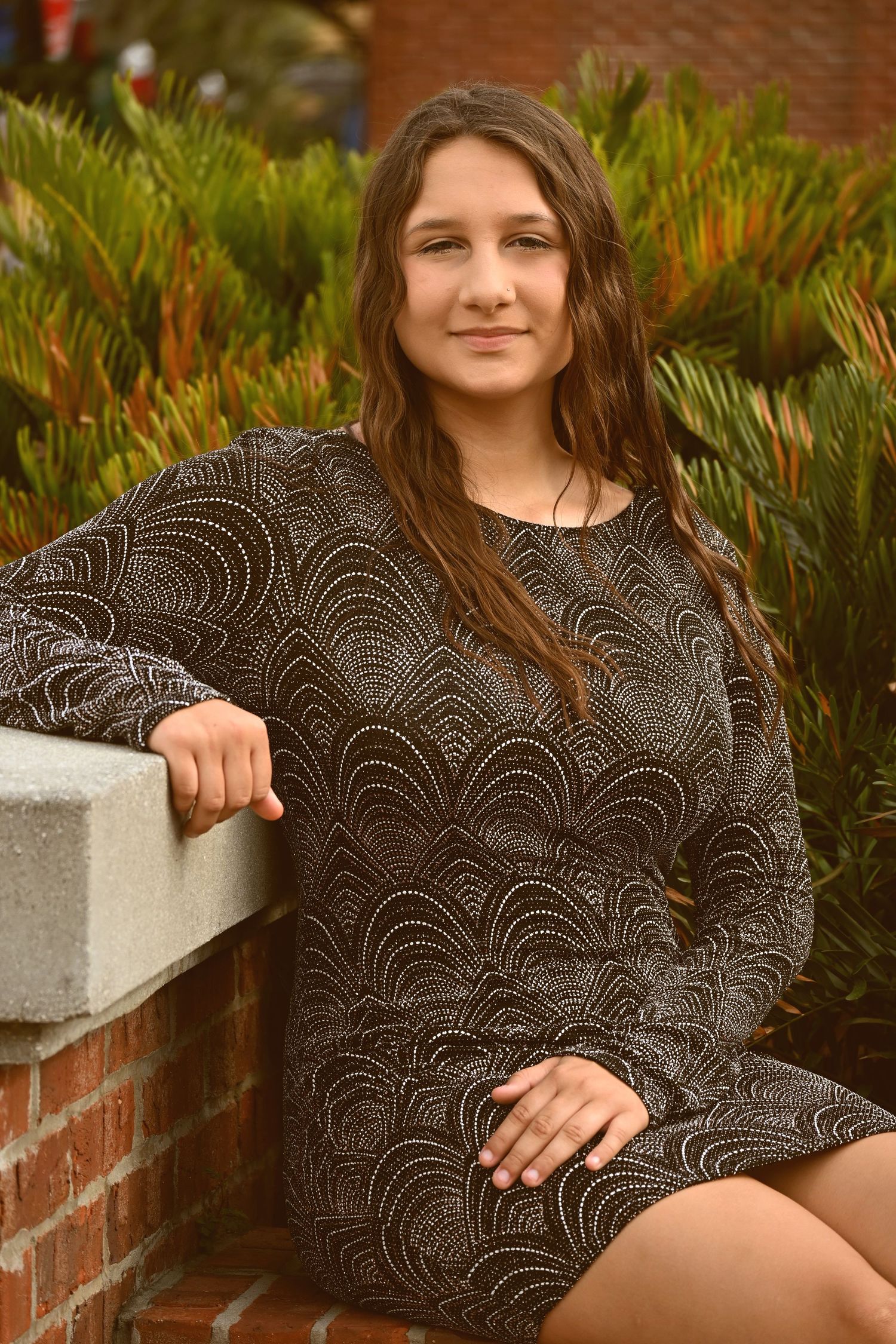 Senior girl seated outdoors beside a brick wall during a portrait session by a Central Florida Photographer.