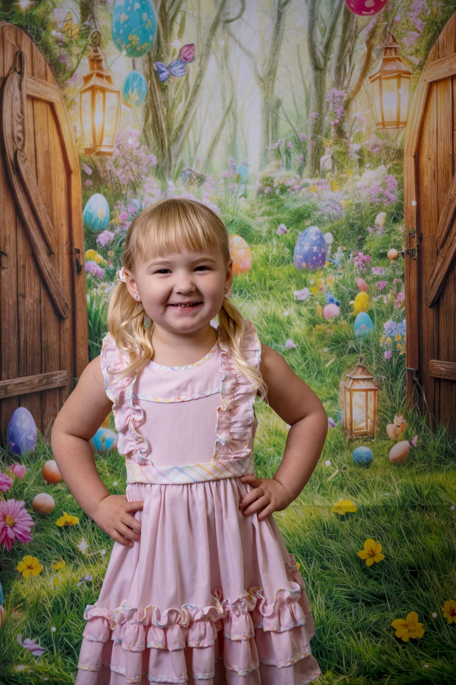 Smiling young girl in a pink dress posing in a whimsical garden-themed studio set by a Central Florida Photographer.