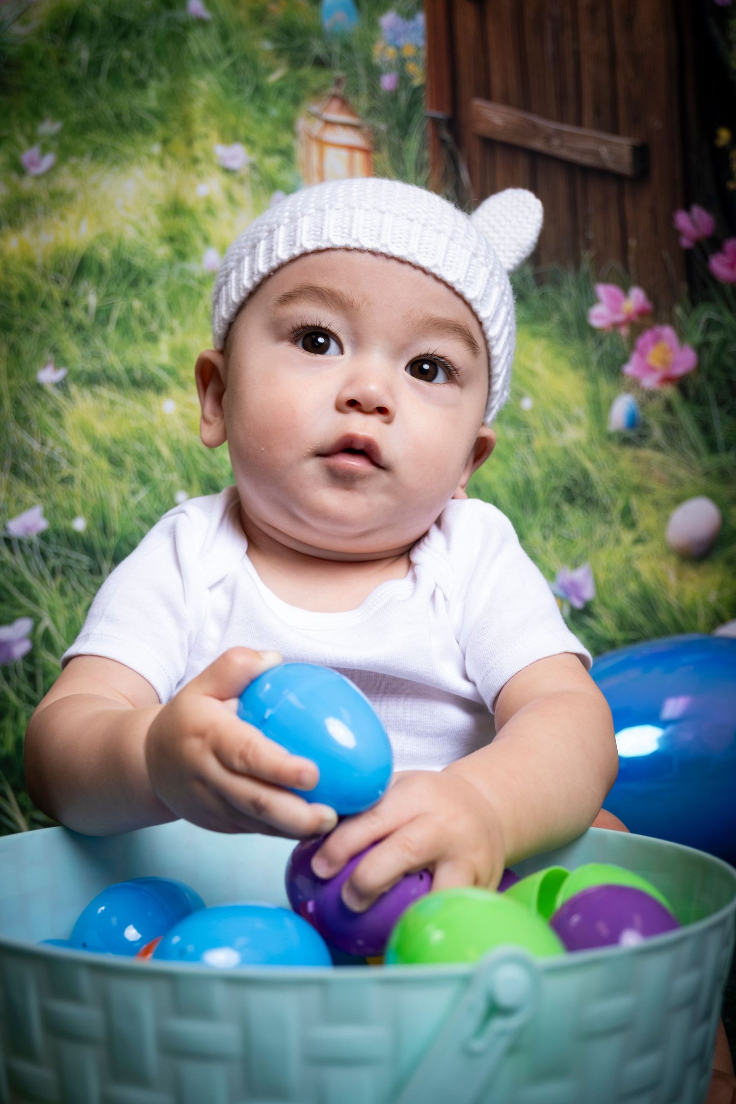 Baby surrounded by colorful Easter eggs during a spring milestone session by a Central Florida Photographer.
