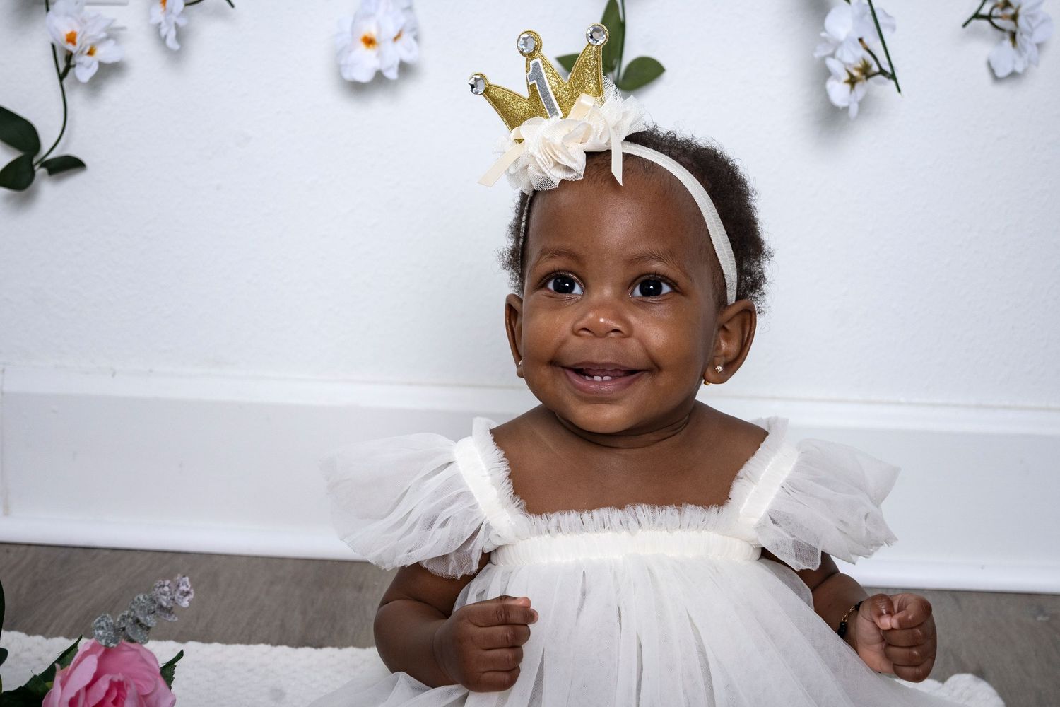 Smiling baby girl in a white dress during a milestone portrait session by a Central Florida Photographer.