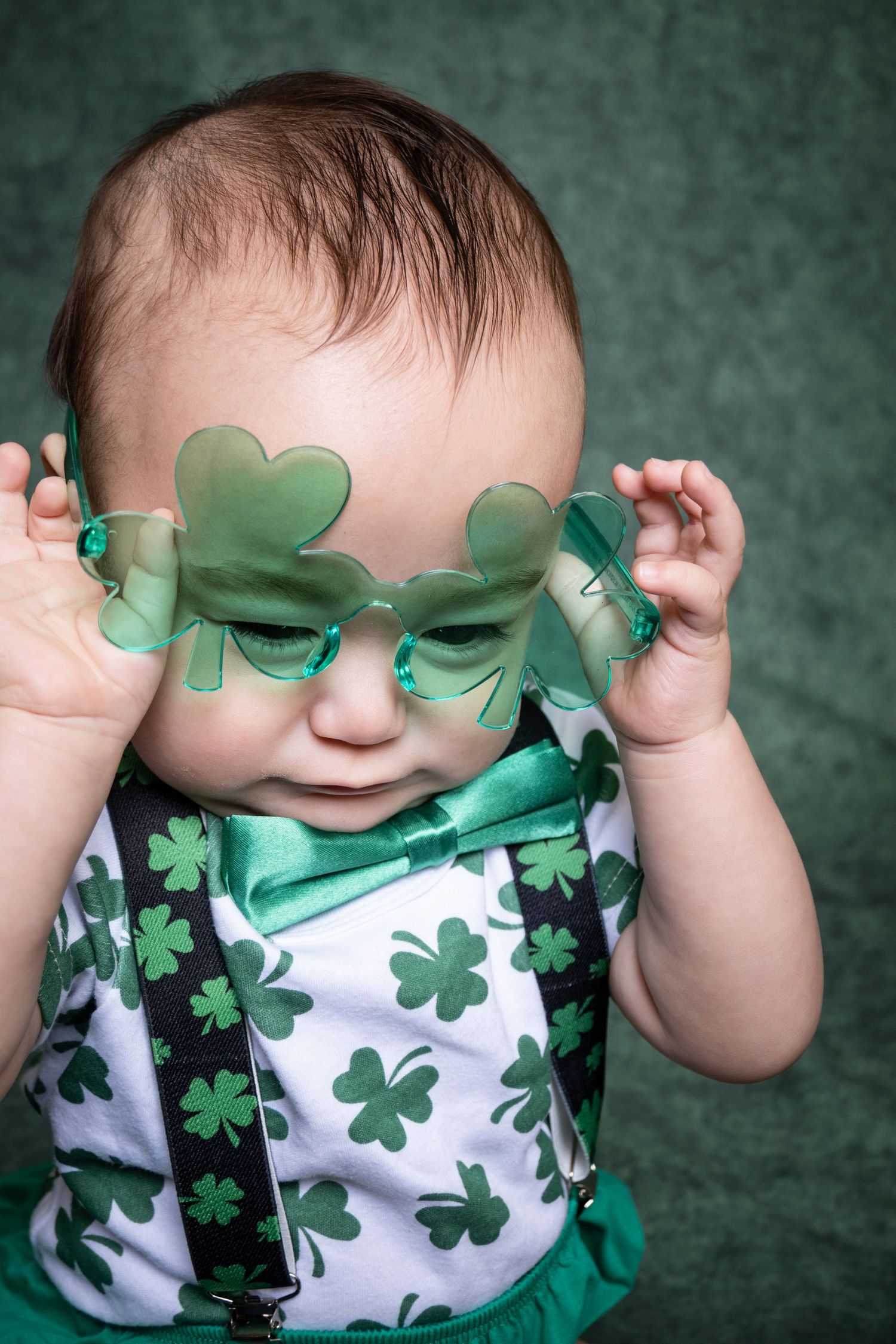 Baby wearing shamrock glasses and festive green attire during a St. Patrick's Day portrait by a Central Florida Photographer.