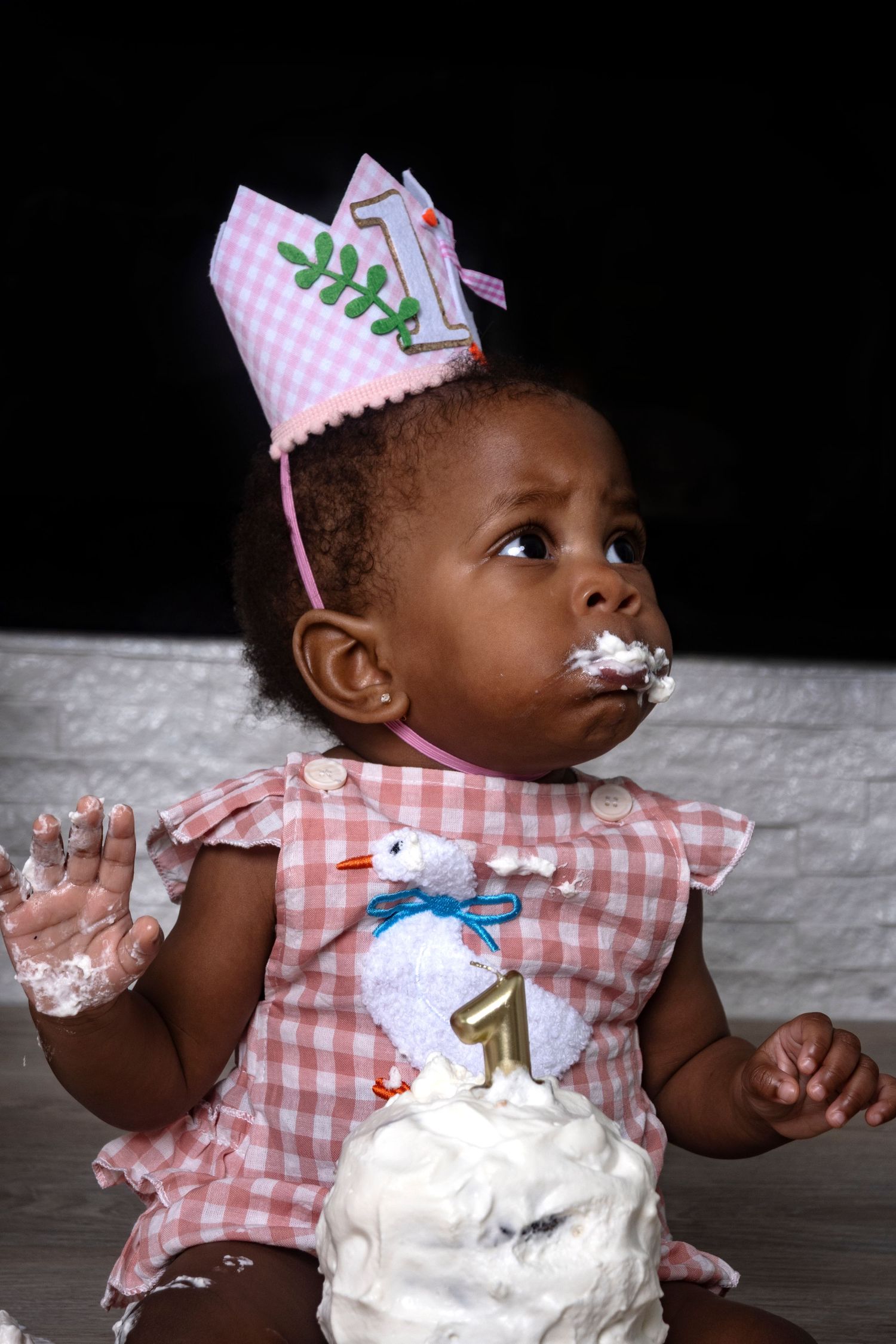 Baby girl wearing a birthday crown enjoying cake during a first birthday cake smash by a Central Florida Photographer.
