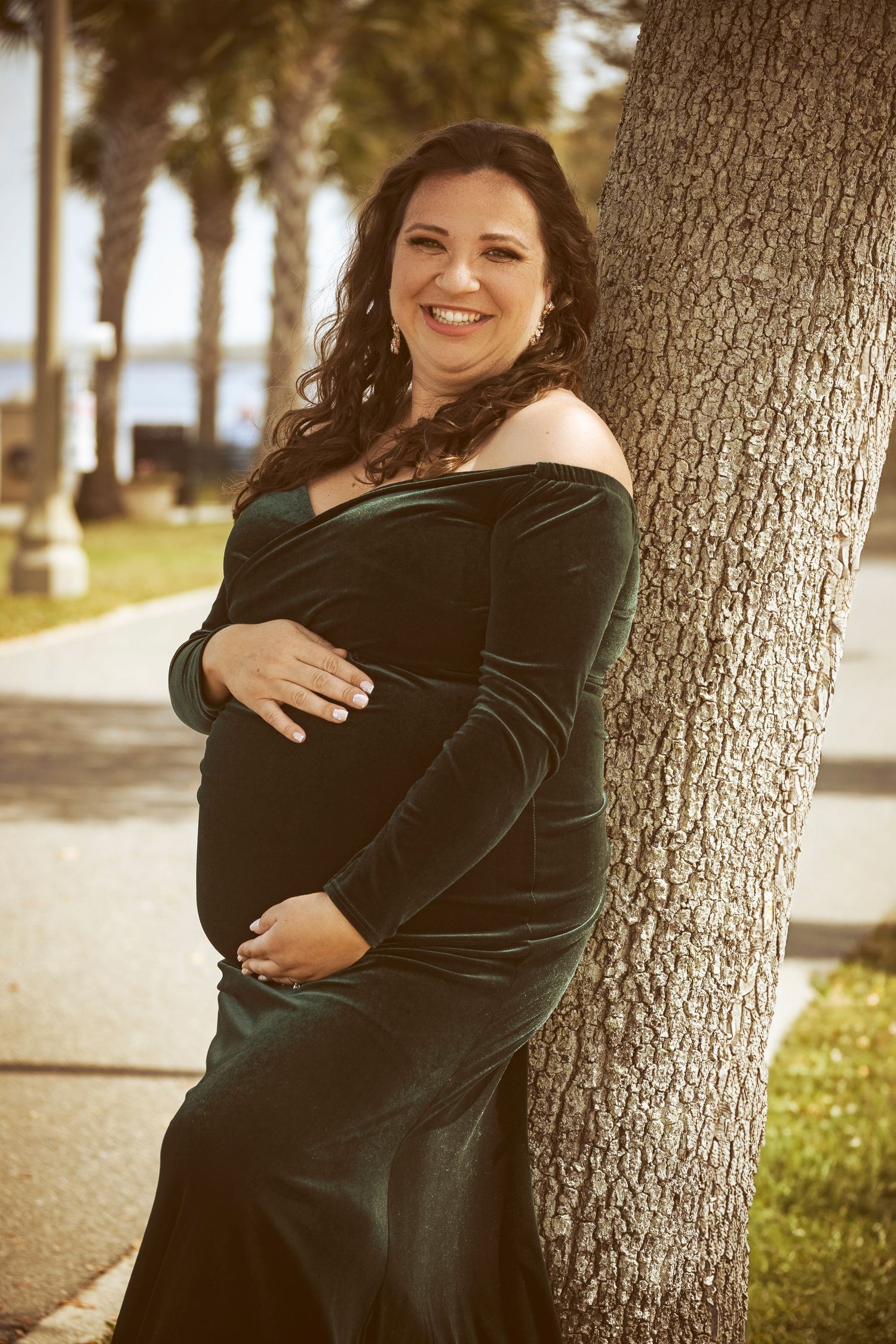 Expectant mother posing beside a tree during an outdoor maternity session by a Central Florida Photographer.