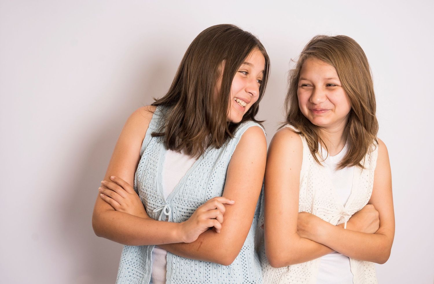 Two sisters laughing together during a studio sibling portrait session by a Central Florida Photographer.