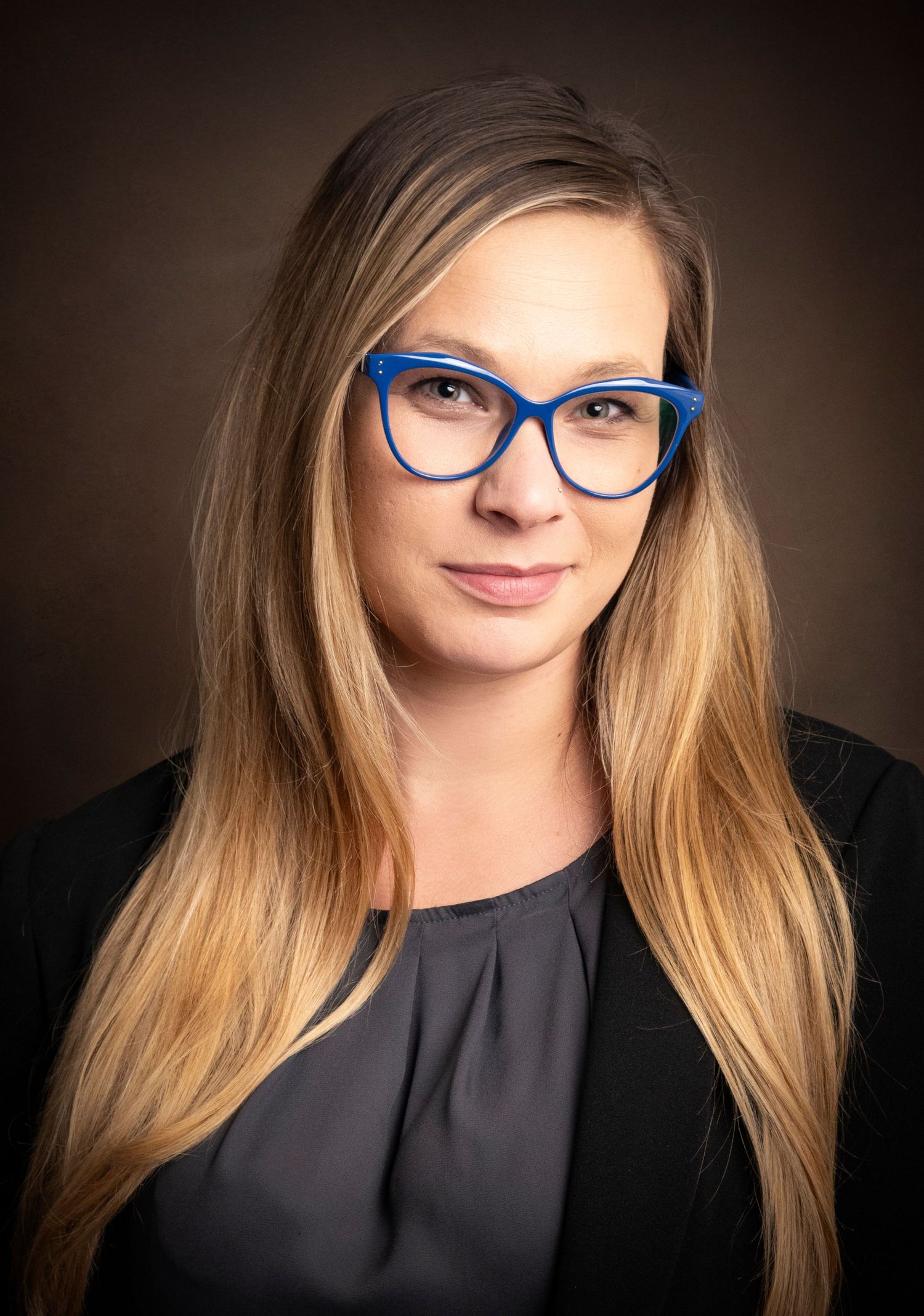 Corporate headshot of a woman wearing blue glasses by a Central Florida Photographer.