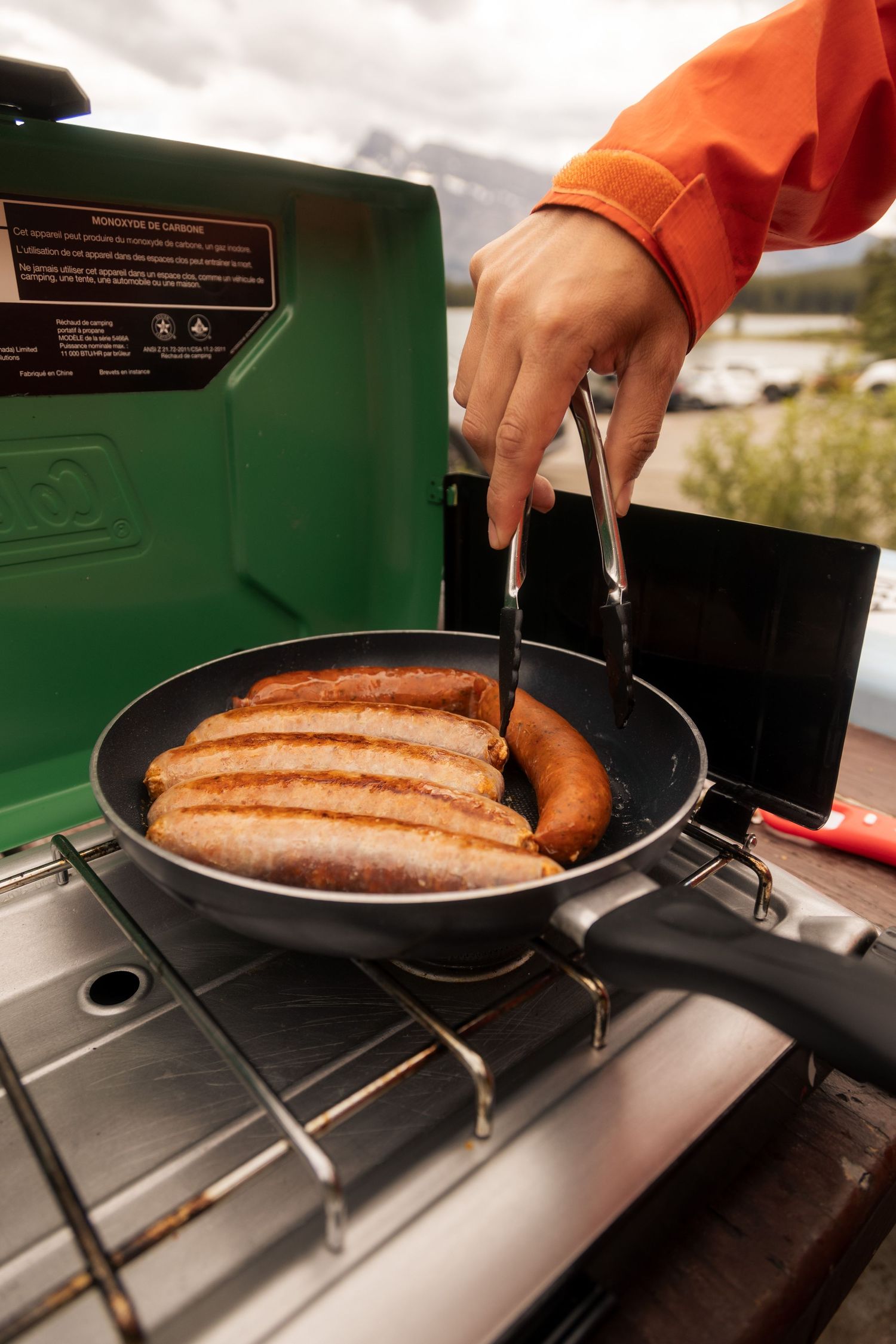 Une personne faisant cuire des saucisses sur un BBQ de camping — Jonathan Ouimet Photographie