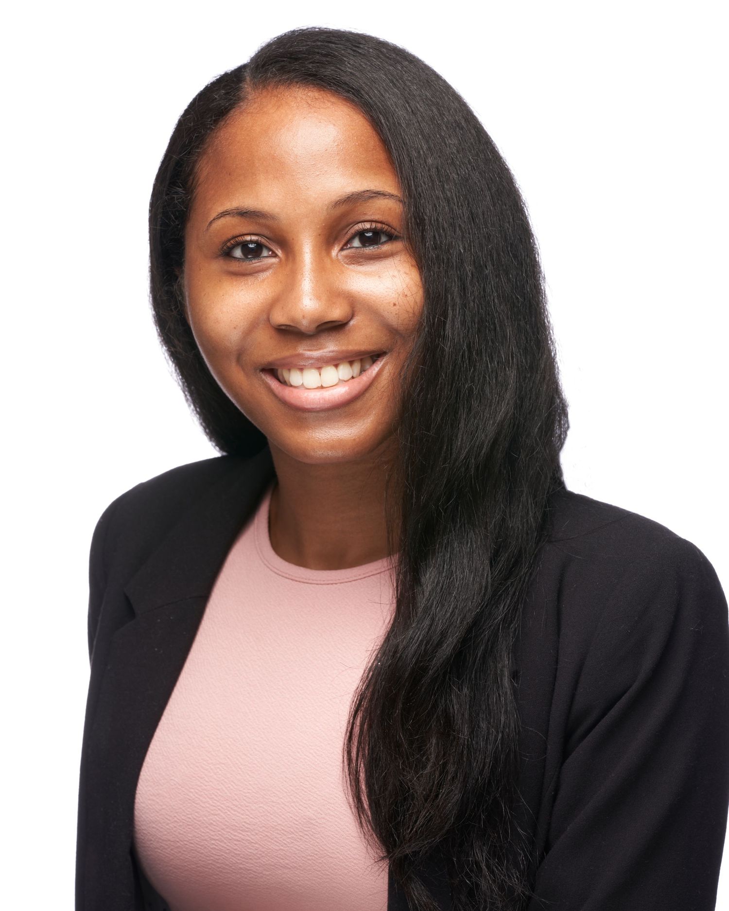A young woman in a black blazer and pink top smiles brightly against a white background.