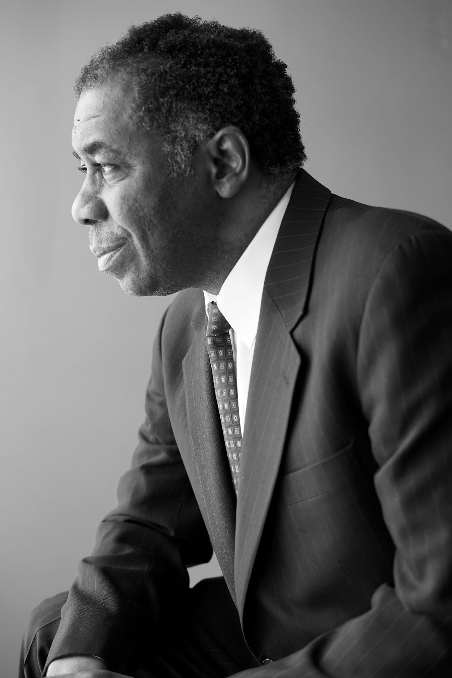 Black and white portrait of a senior Black businessman in suit and tie looking to the side.