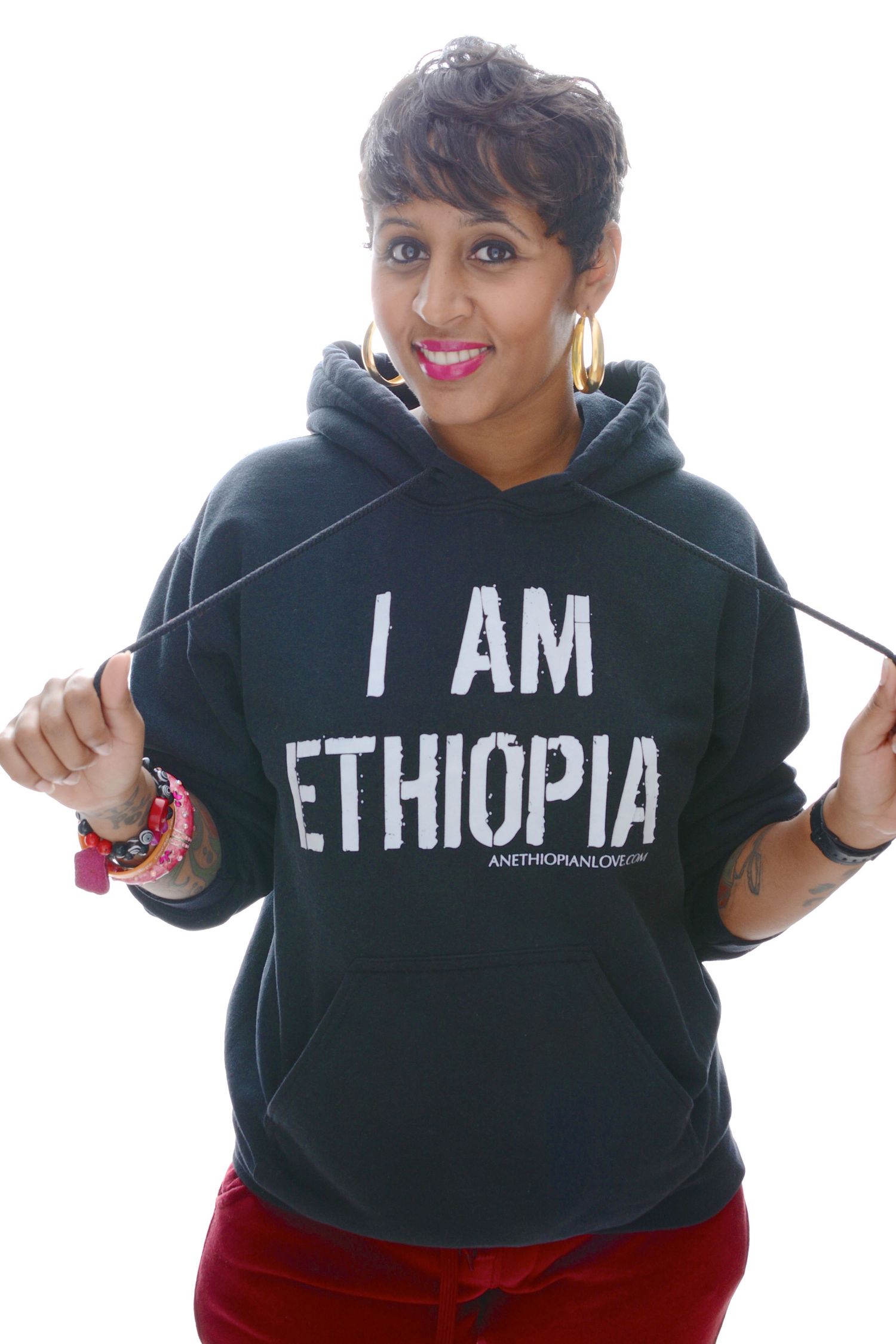 Smiling woman wearing a dark hoodie that reads I AM ETHIOPIA on white background.