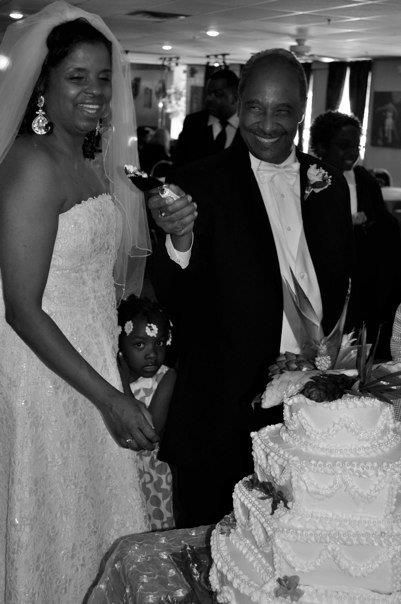Black and white photo of a bride and groom cutting their wedding cake at their reception.