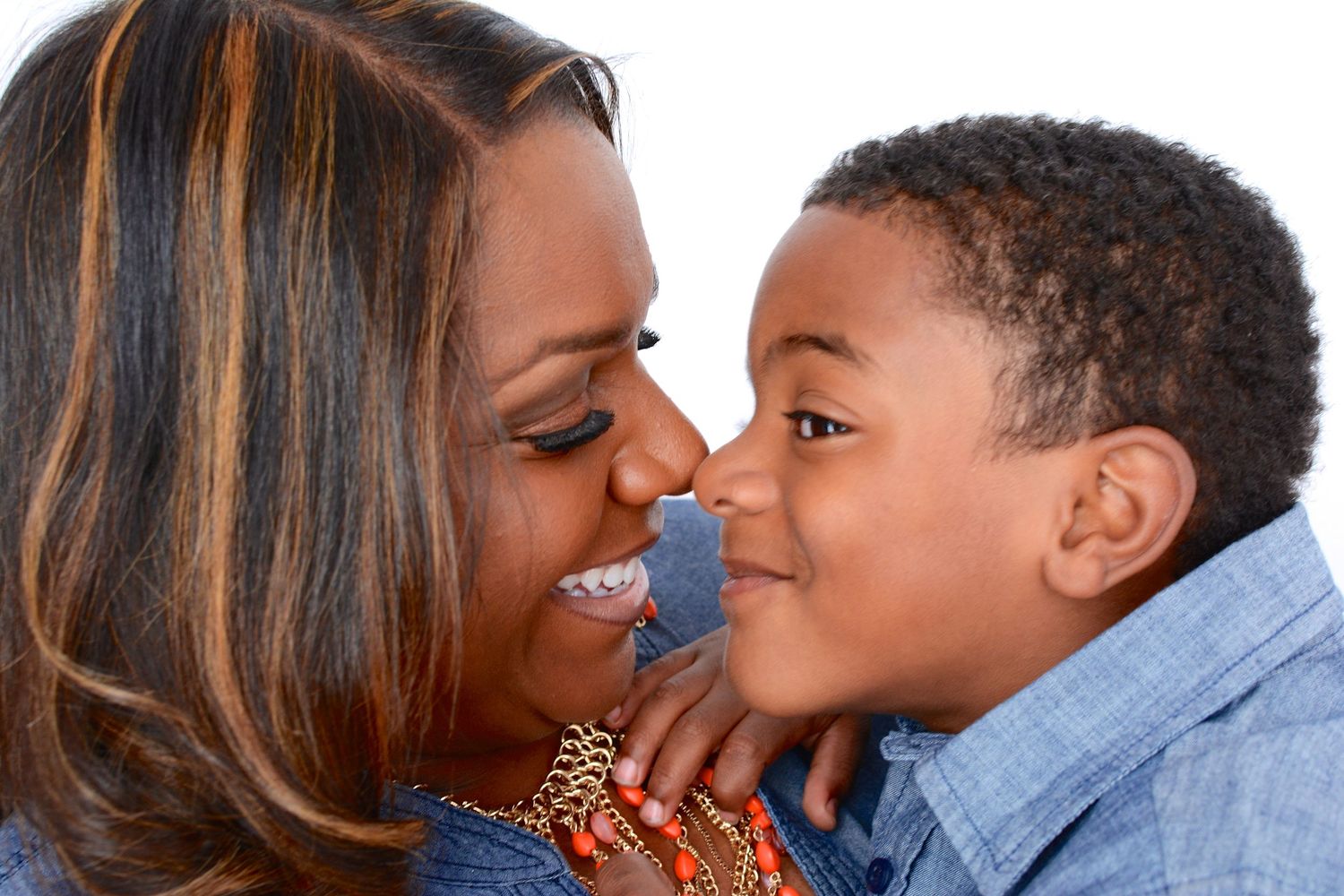 Smiling Black mother and young son sharing a tender nose-to-nose moment.