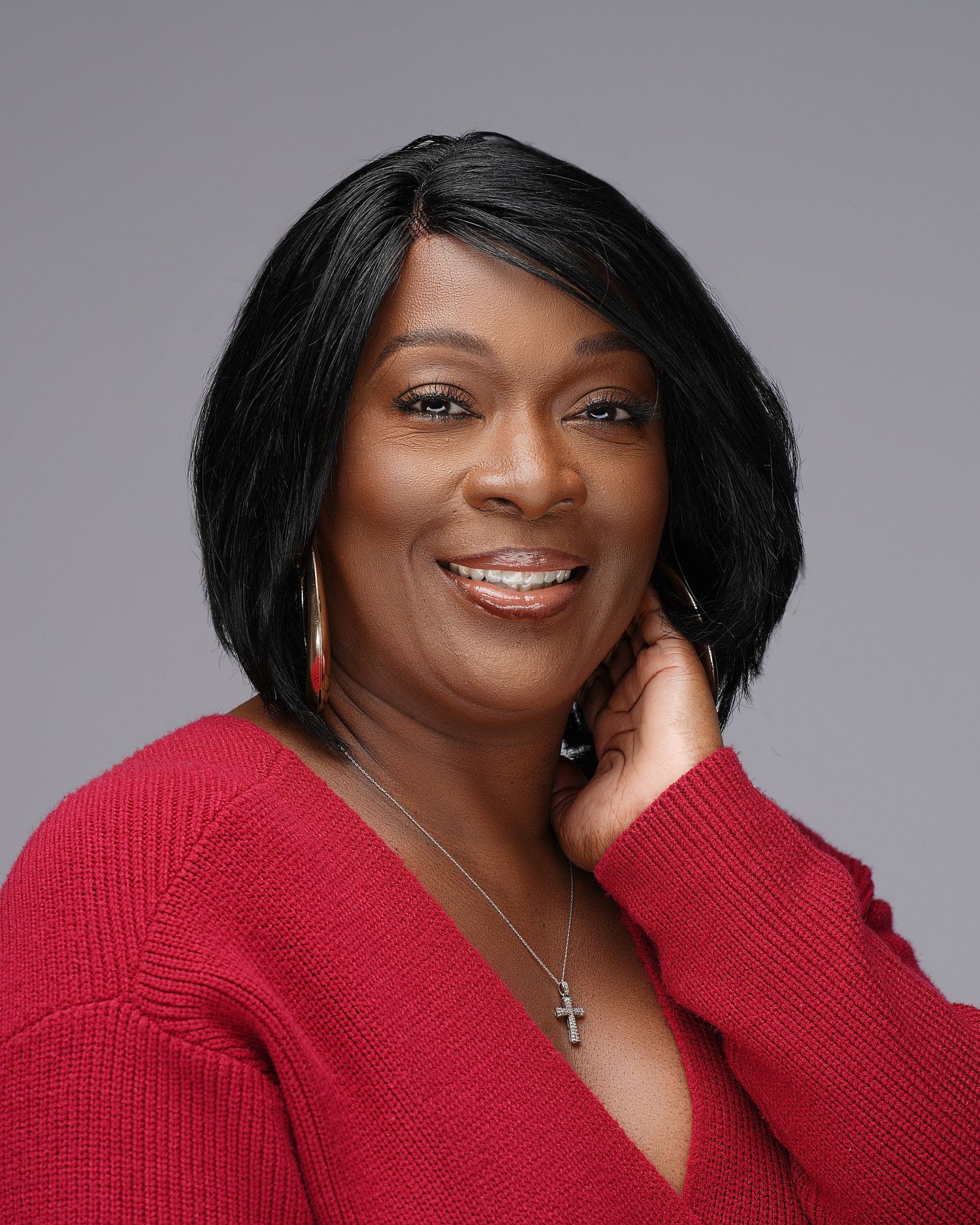 Woman in red sweater with black bob hairstyle smiling in professional headshot.