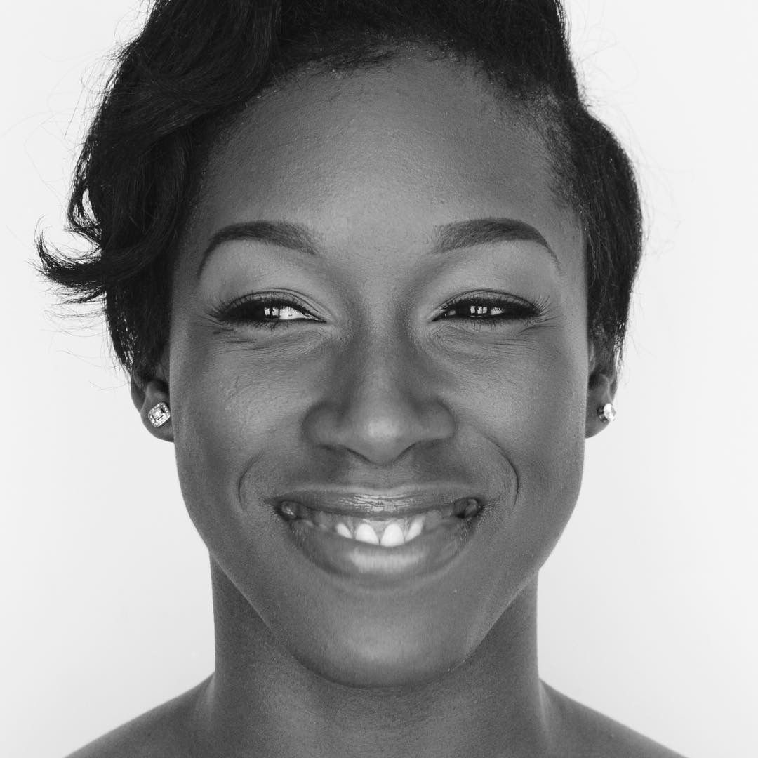 Black and white close-up portrait of a smiling young Black woman with short hair.