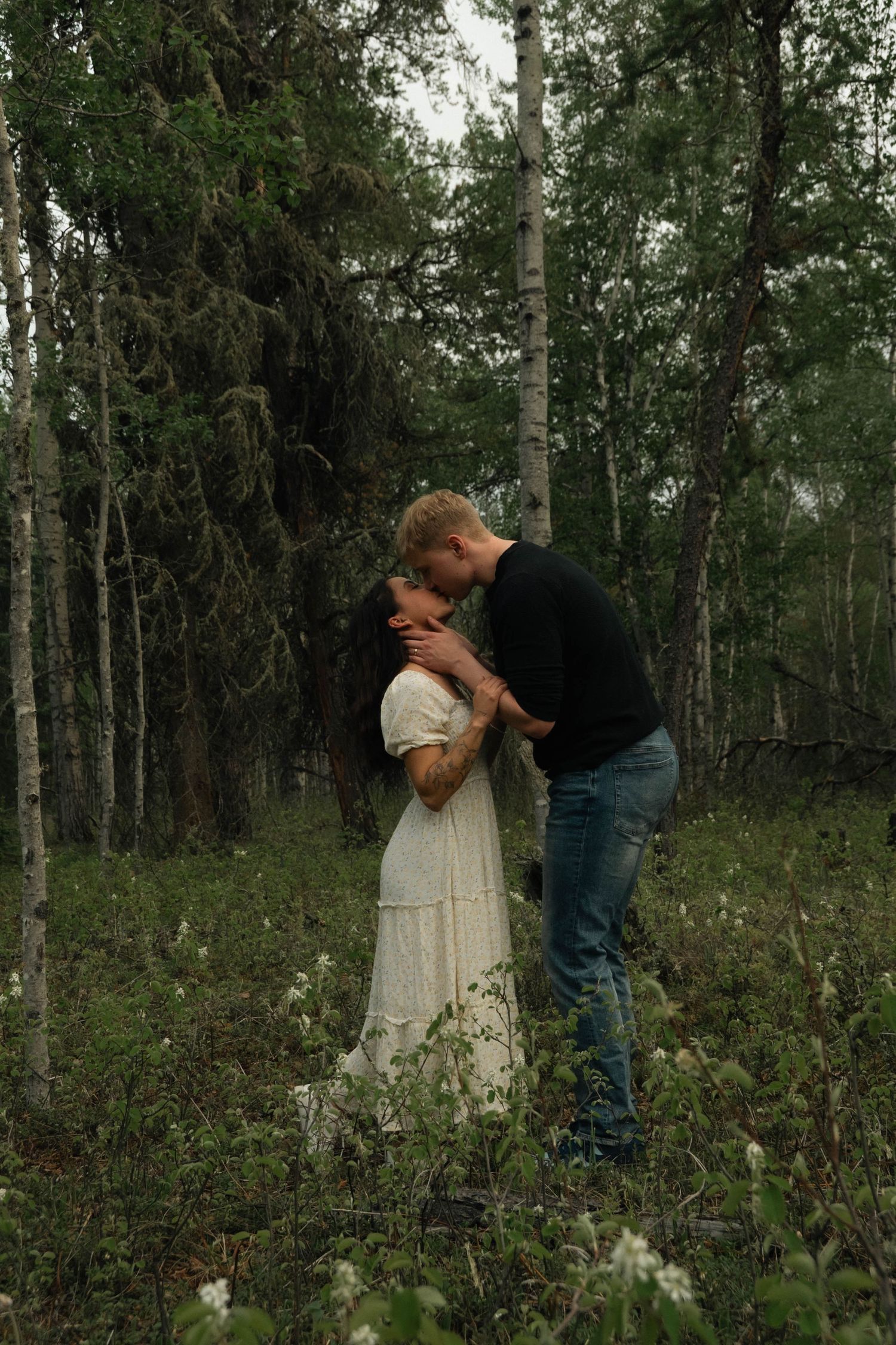 Colour image of colour embracing in the forest, very green.  Tall trees in background.