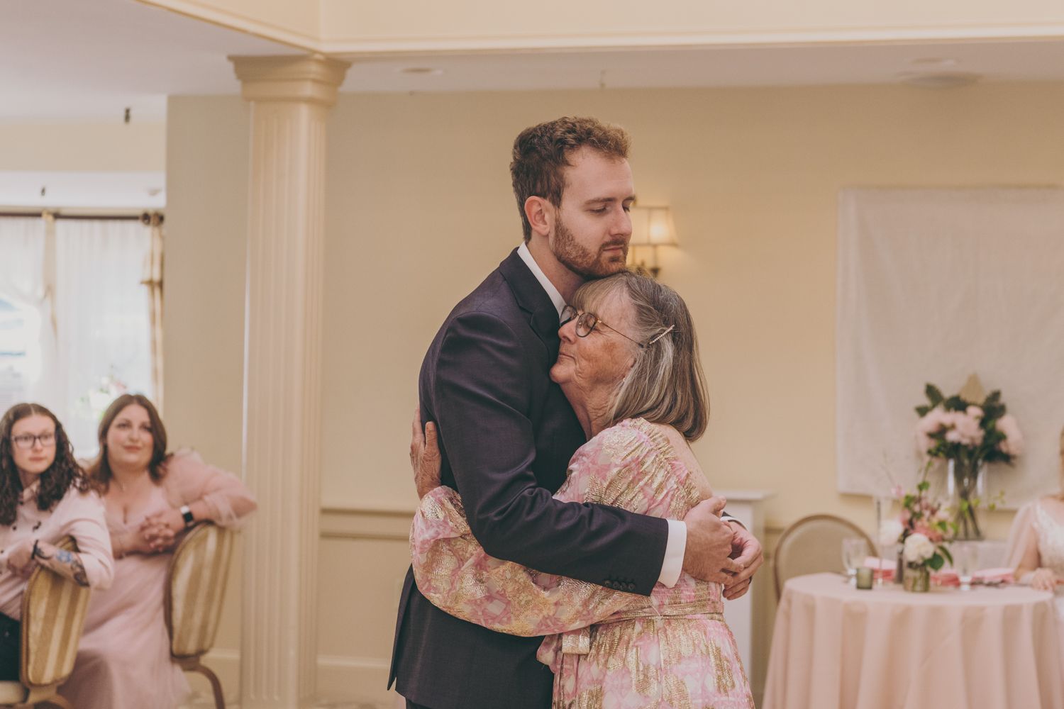 Groom shares a heartfelt mother-son dance embrace during wedding reception in elegant ballroom venue.