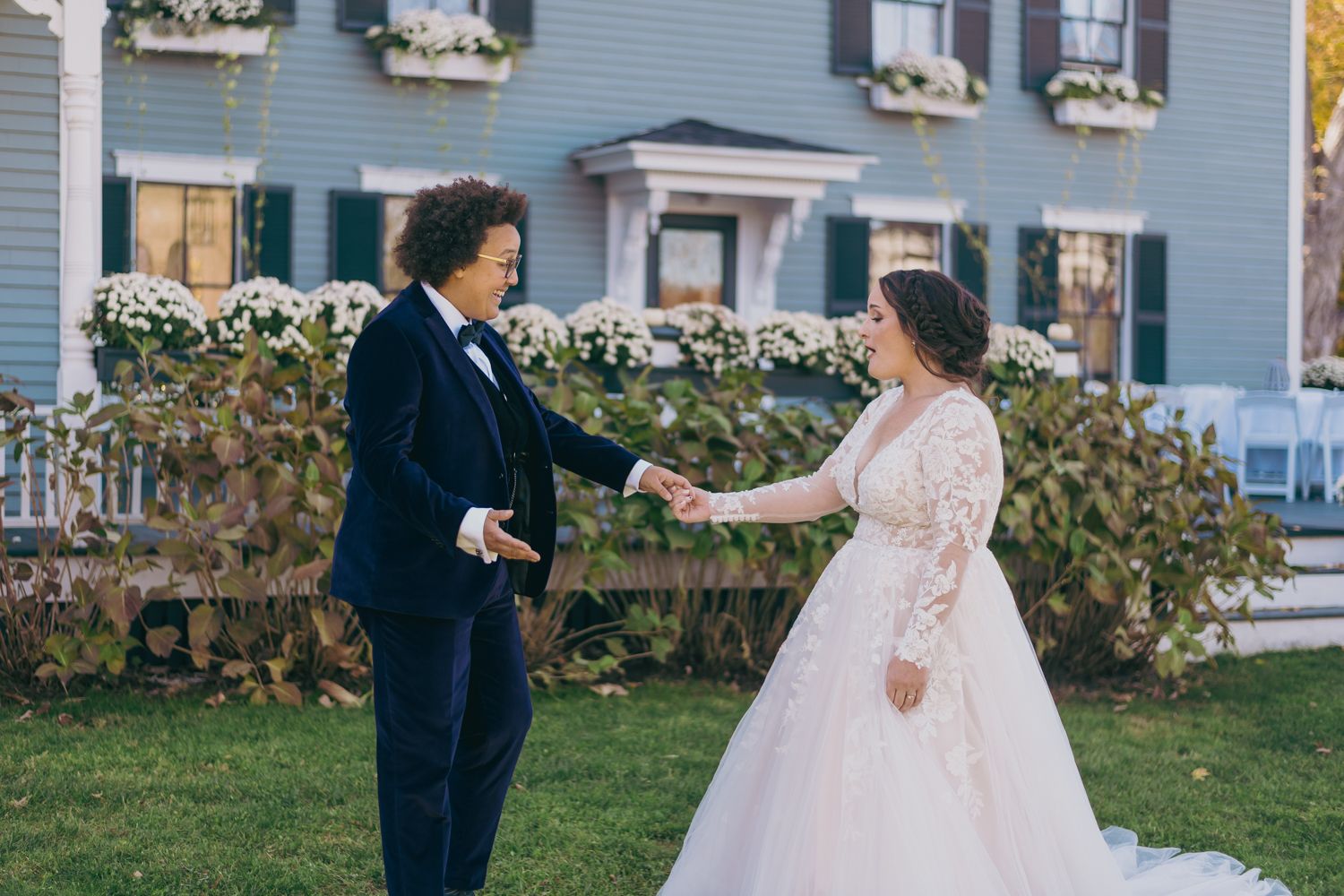 Bride and groom sharing first look moment outside elegant white colonial home.
