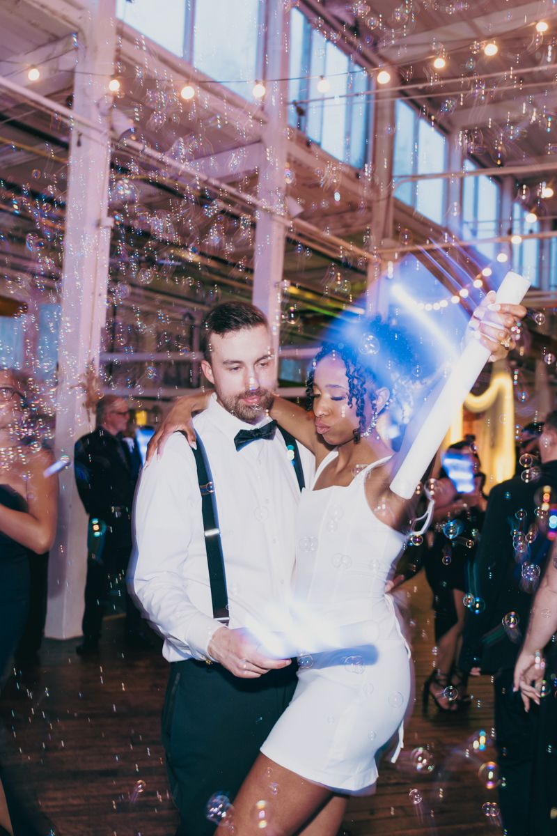 Couple shares first dance surrounded by bubbles at elegant wedding reception venue.