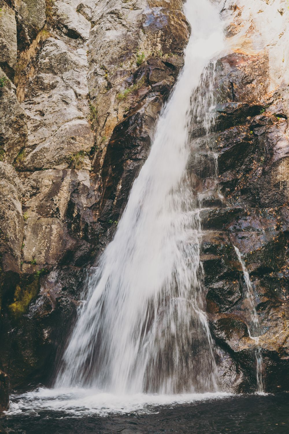 Scenic waterfall cascading over moss-covered rocks in a natural outdoor setting.