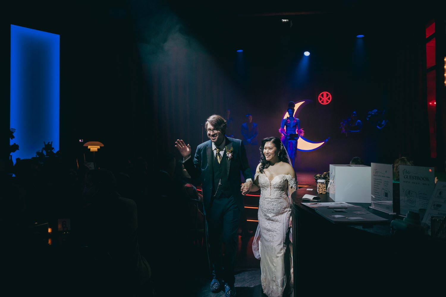 Bride and groom making grand entrance at dark, moody wedding reception venue.