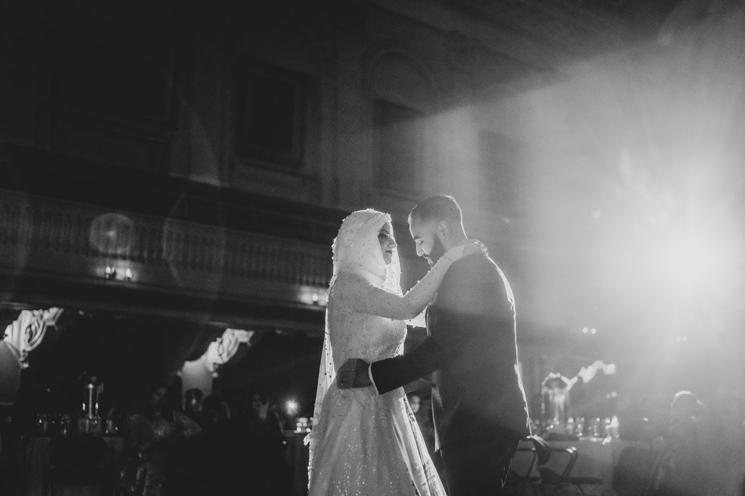 Black and white photo of a bride and groom sharing their first dance at an elegant wedding reception.