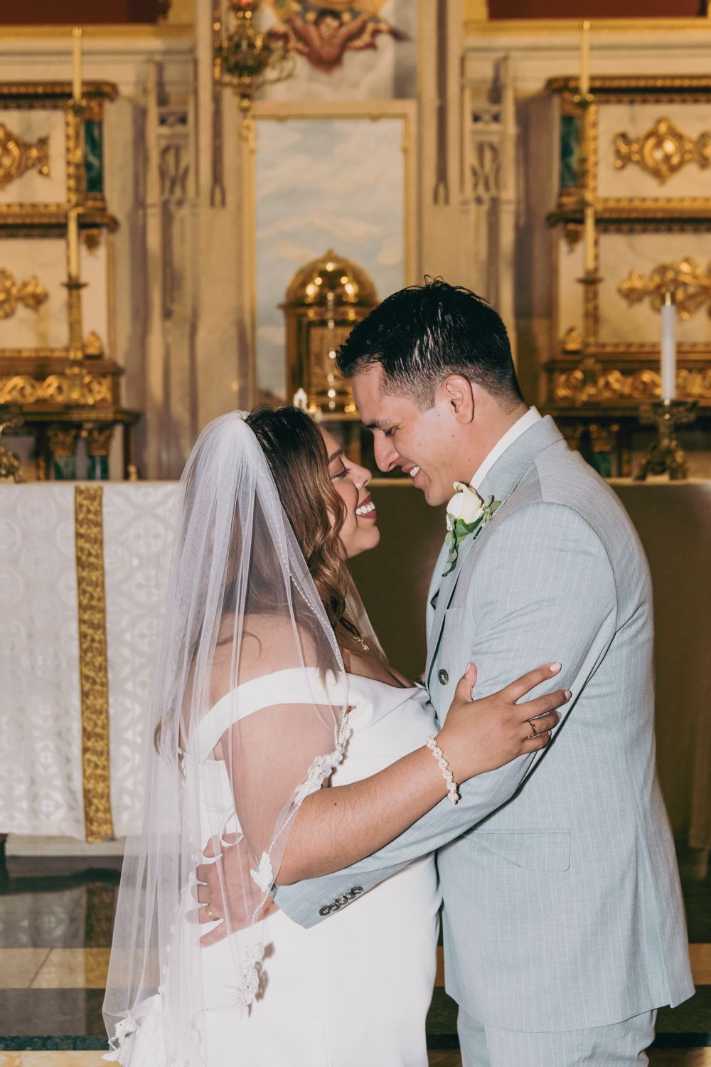 Bride and groom share a joyful moment at the altar inside a beautiful ornate church.