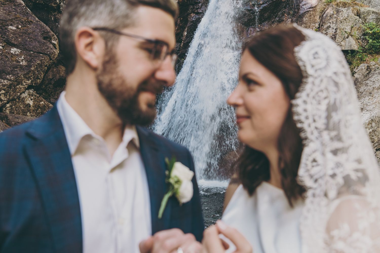 Bride and groom share a romantic moment in front of a waterfall on their wedding day.