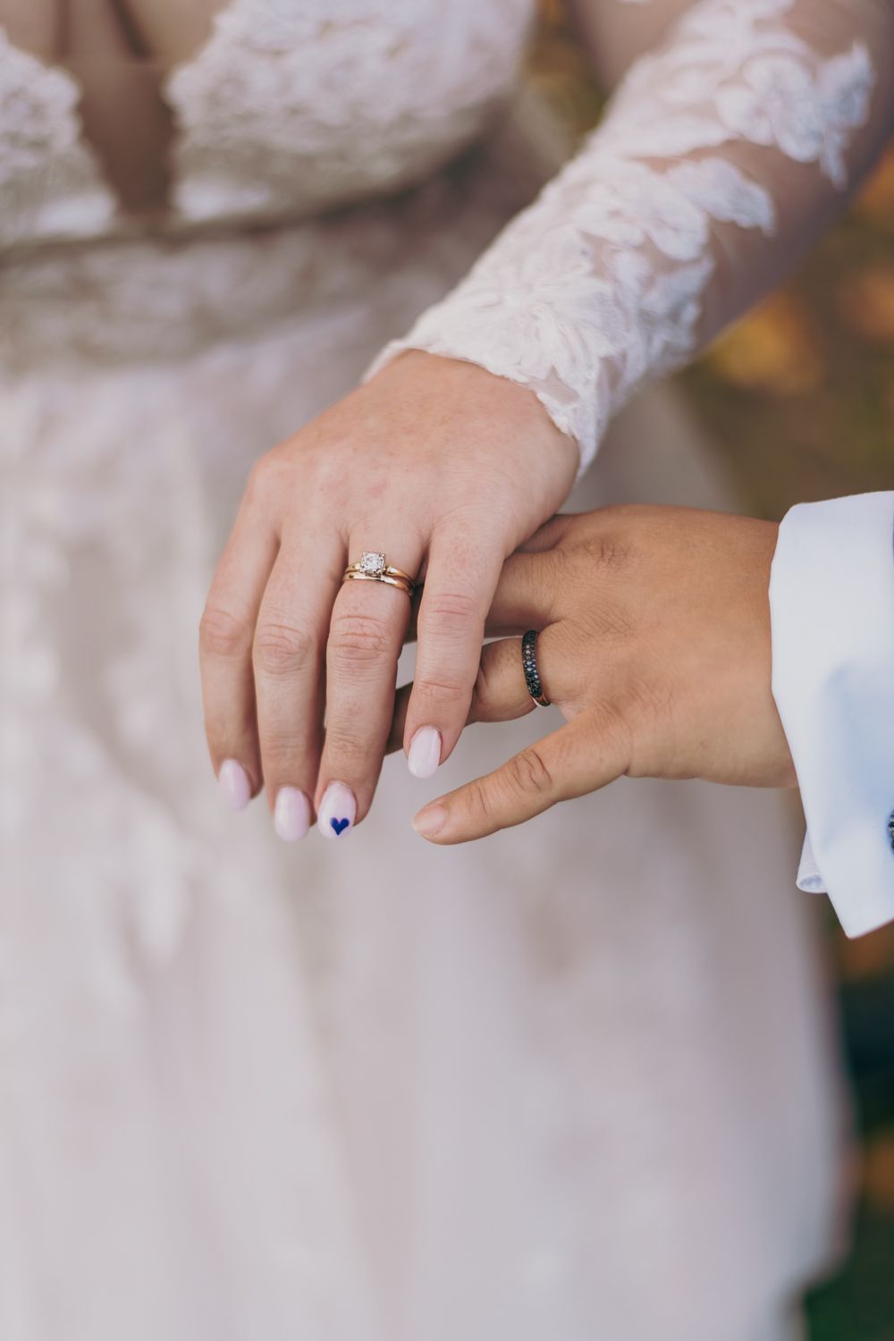 Close-up of bride and groom showing wedding rings, bride wearing diamond engagement ring.