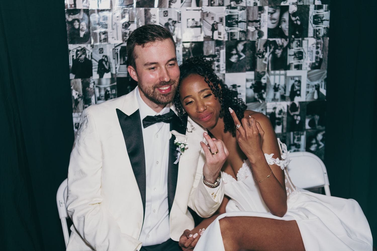 Smiling newlywed couple posing in front of black and white photo booth backdrop.