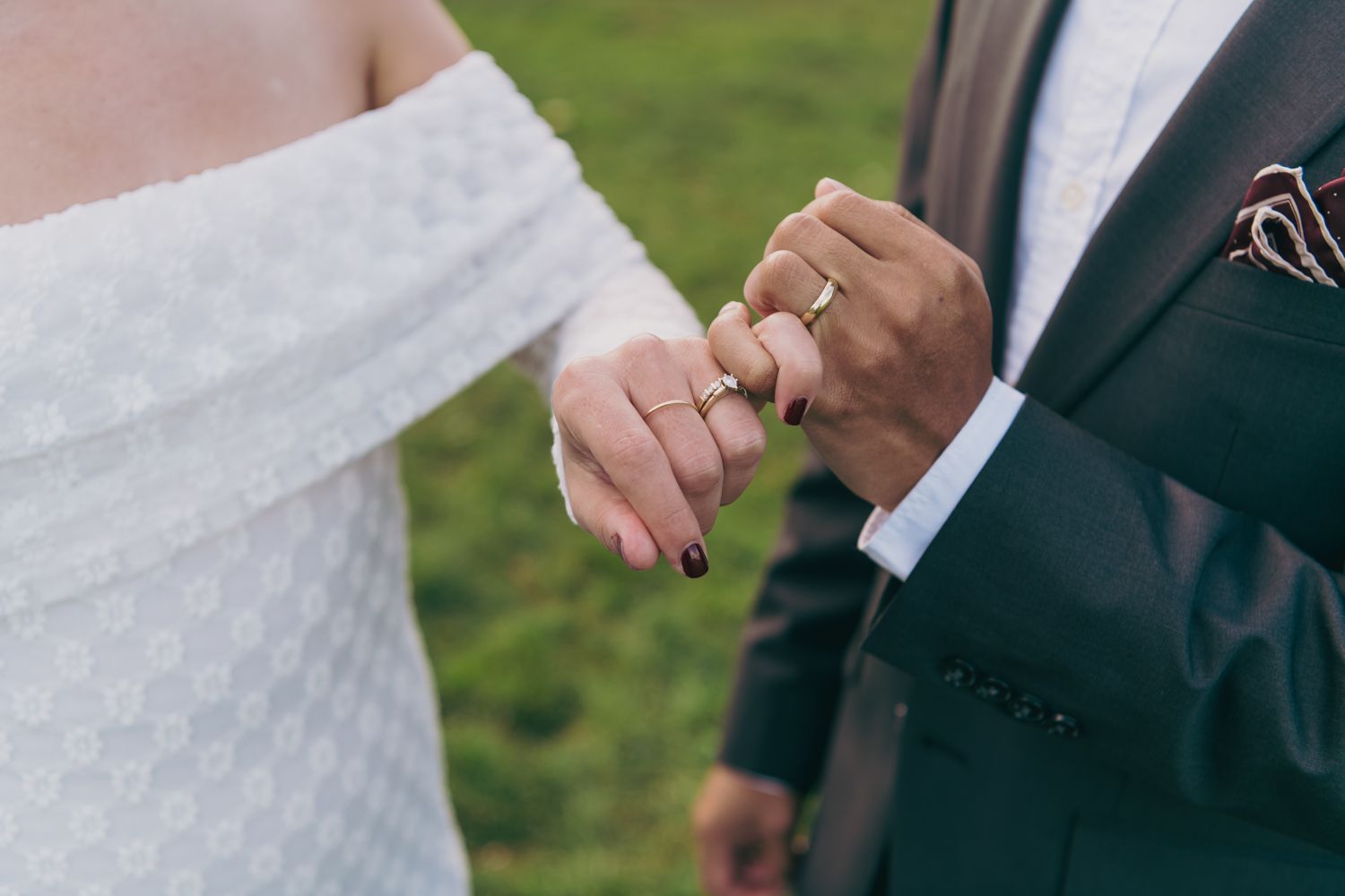 Close-up of interracial couple holding hands with wedding rings on their wedding day.