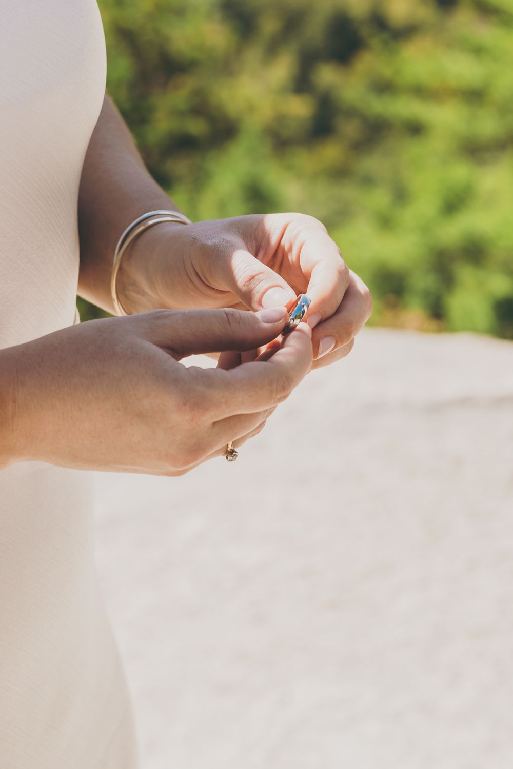Close-up of brides hands holding a delicate blue gemstone wedding ring.