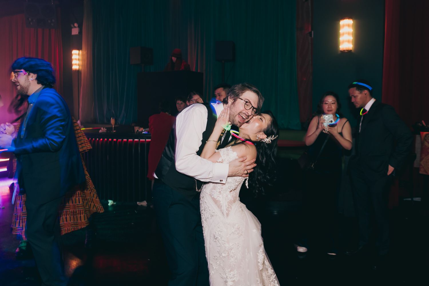 Bride and groom sharing romantic dance embrace at dimly lit wedding reception.