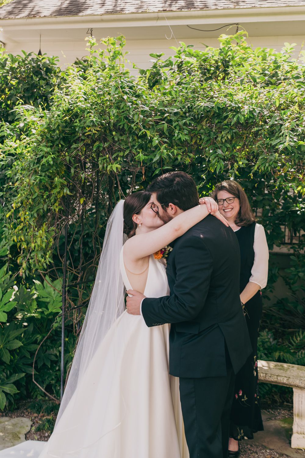 Newlyweds share their first kiss as husband and wife at an outdoor garden wedding ceremony.