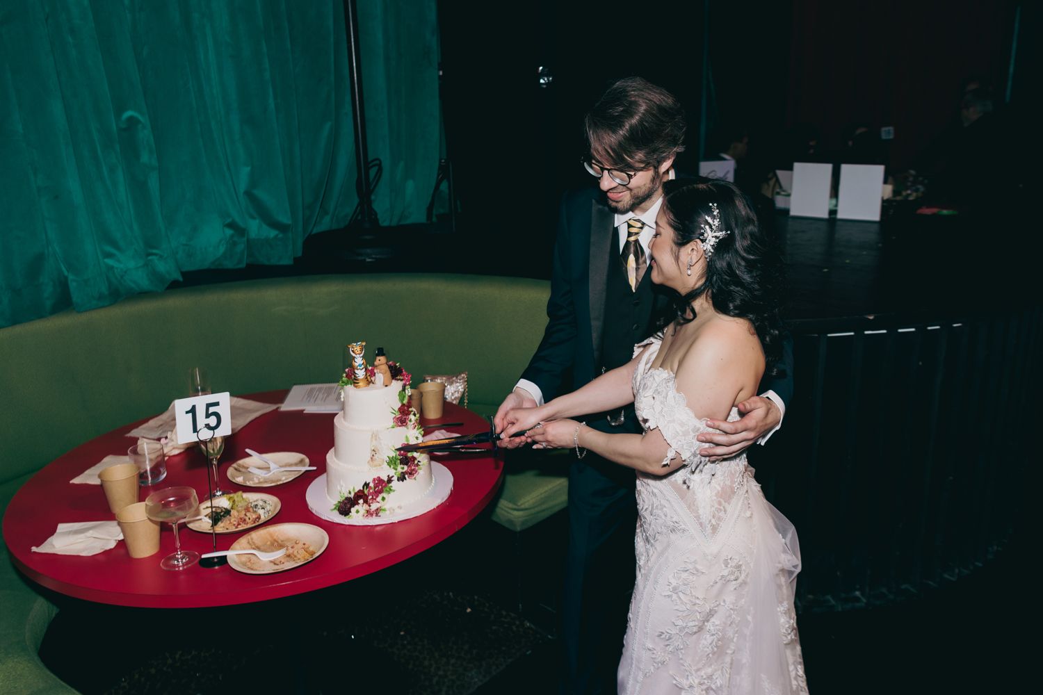 Bride and groom cut their white wedding cake together at a romantic reception venue.
