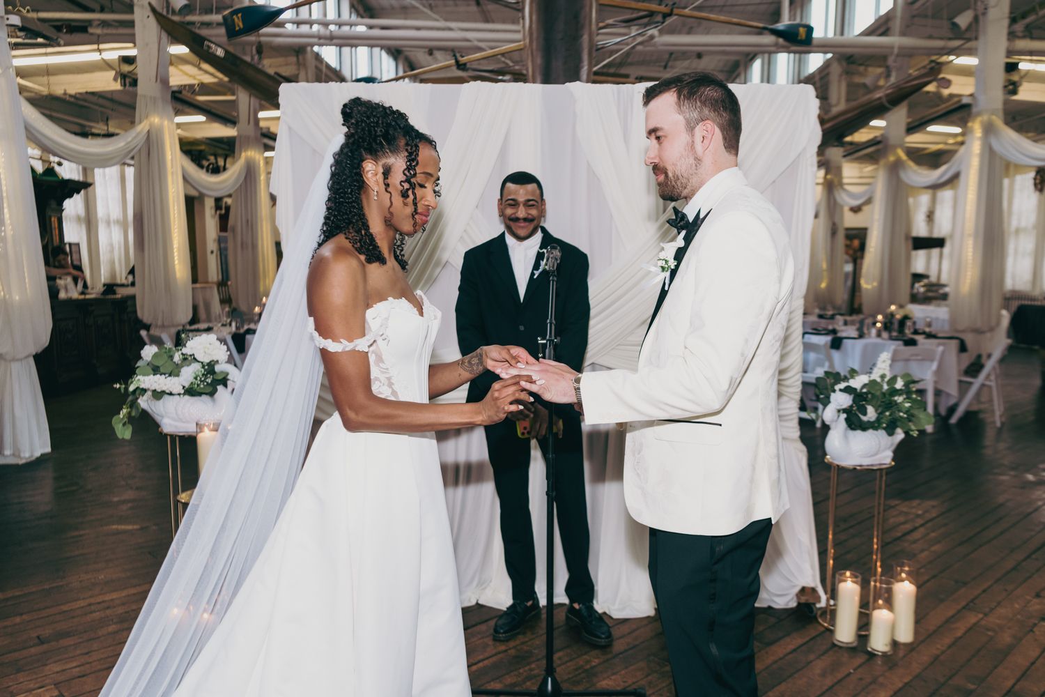 Interracial couple exchanging vows at elegant indoor wedding ceremony with officiant.