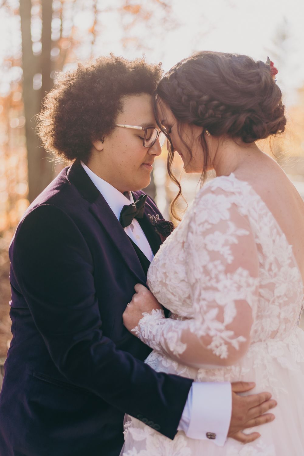 Bride and groom in tender forehead touch moment, golden autumn sunset bokeh background.